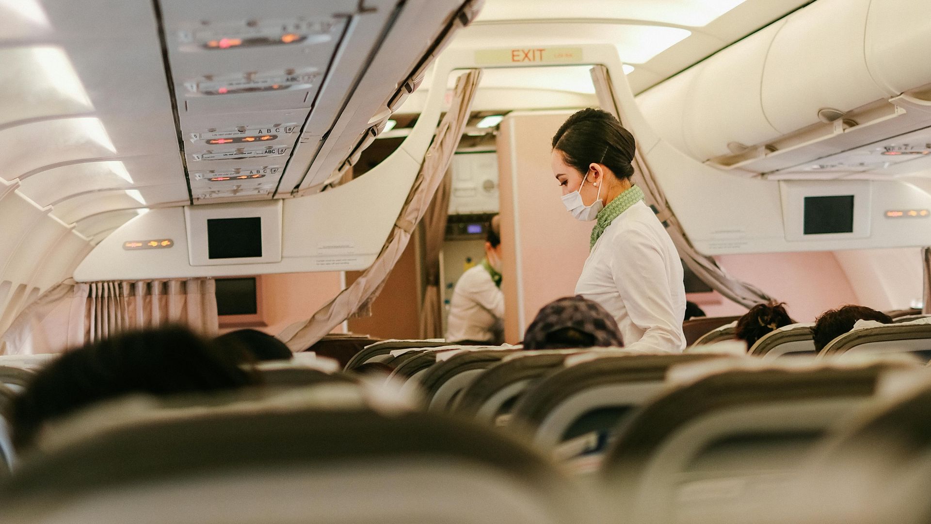Flight attendant serves passengers in an airplane's cabin interior, focusing on customer service during air travel.