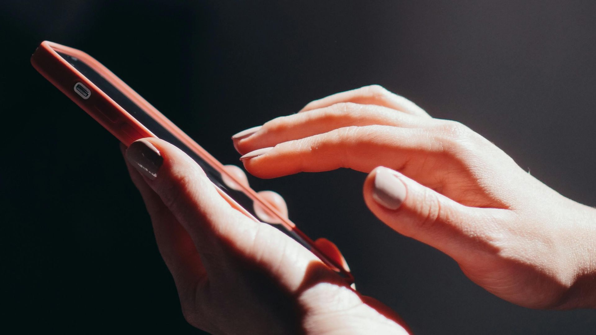 Hands interacting with a smartphone in a well-lit setting, emphasizing connection and technology.
