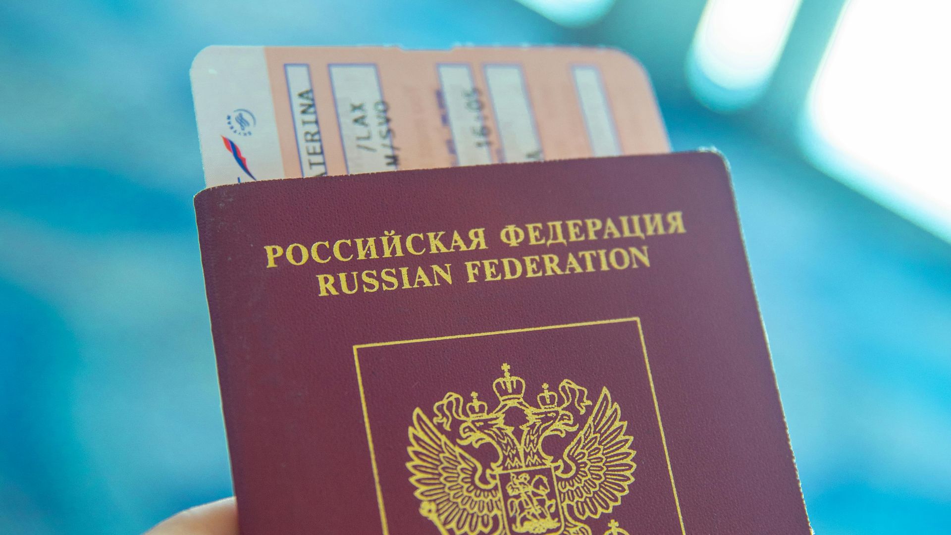 Russian passport held in hand with boarding pass peeking out, ready for travel.
