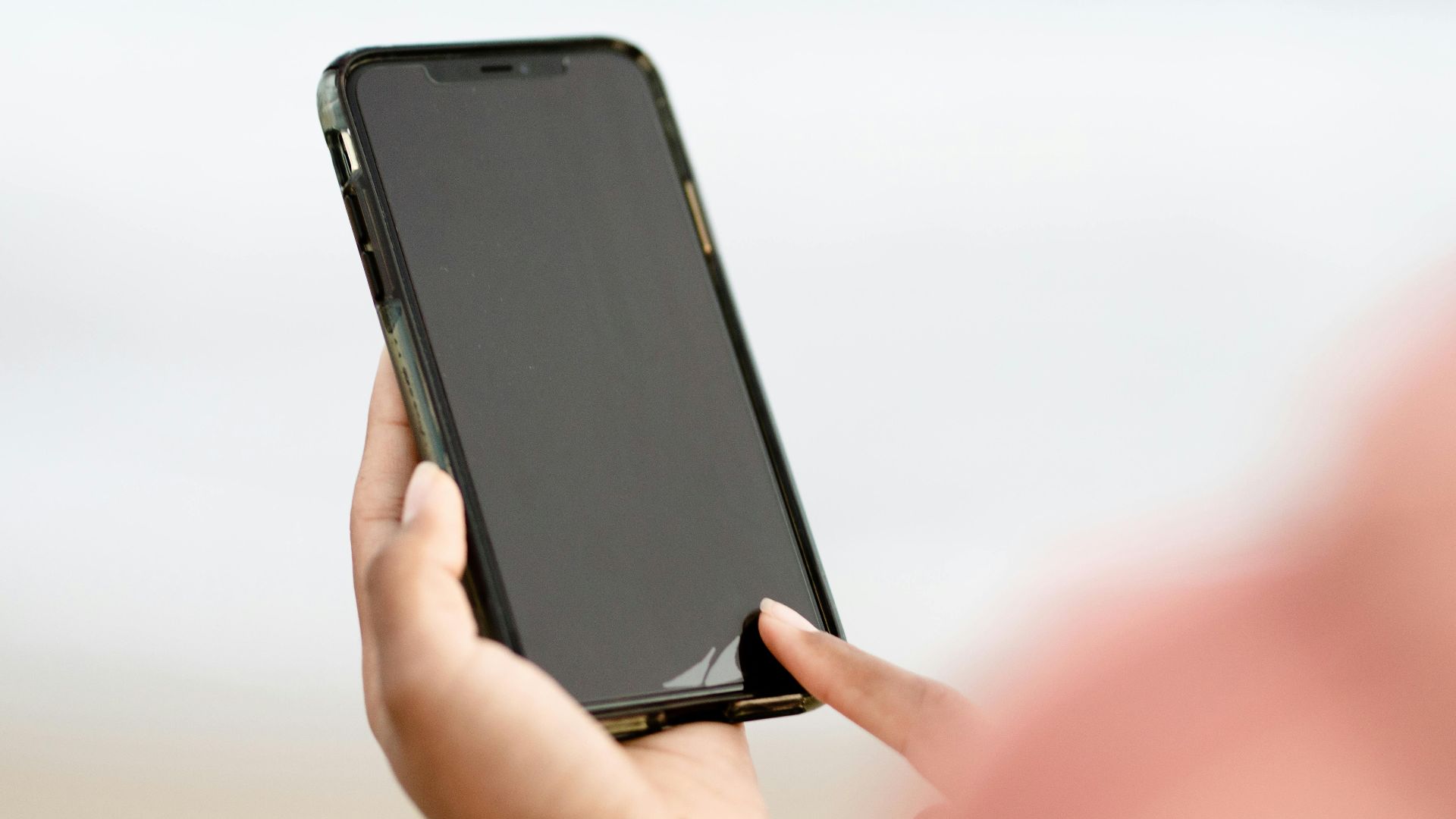 A hand interacting with a smartphone touchscreen outdoors. Modern technology concept.