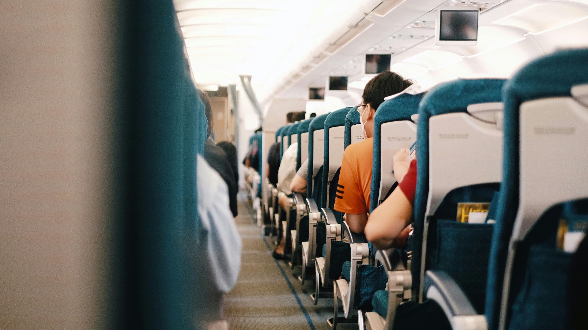 Interior view of airplane cabin showing passengers seated during a flight.