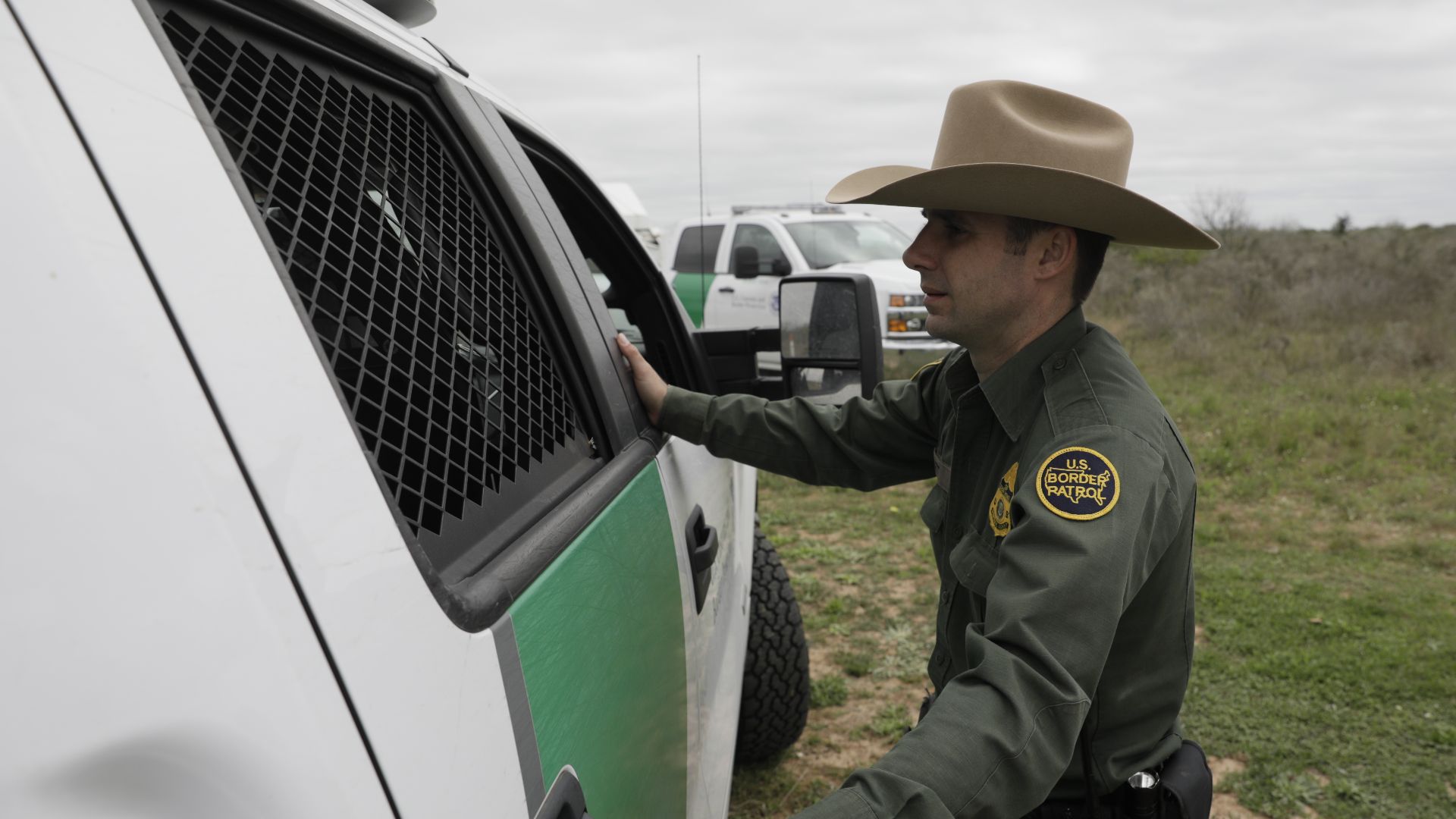 A U.S. Border Patrol agent peers into the backseat of a truck as he closes the door on several captured illegal border crossers near Hebbronville, Texas, March 7, 2019. U.S. Customs and Border Protection Photo by Glenn Fawcett