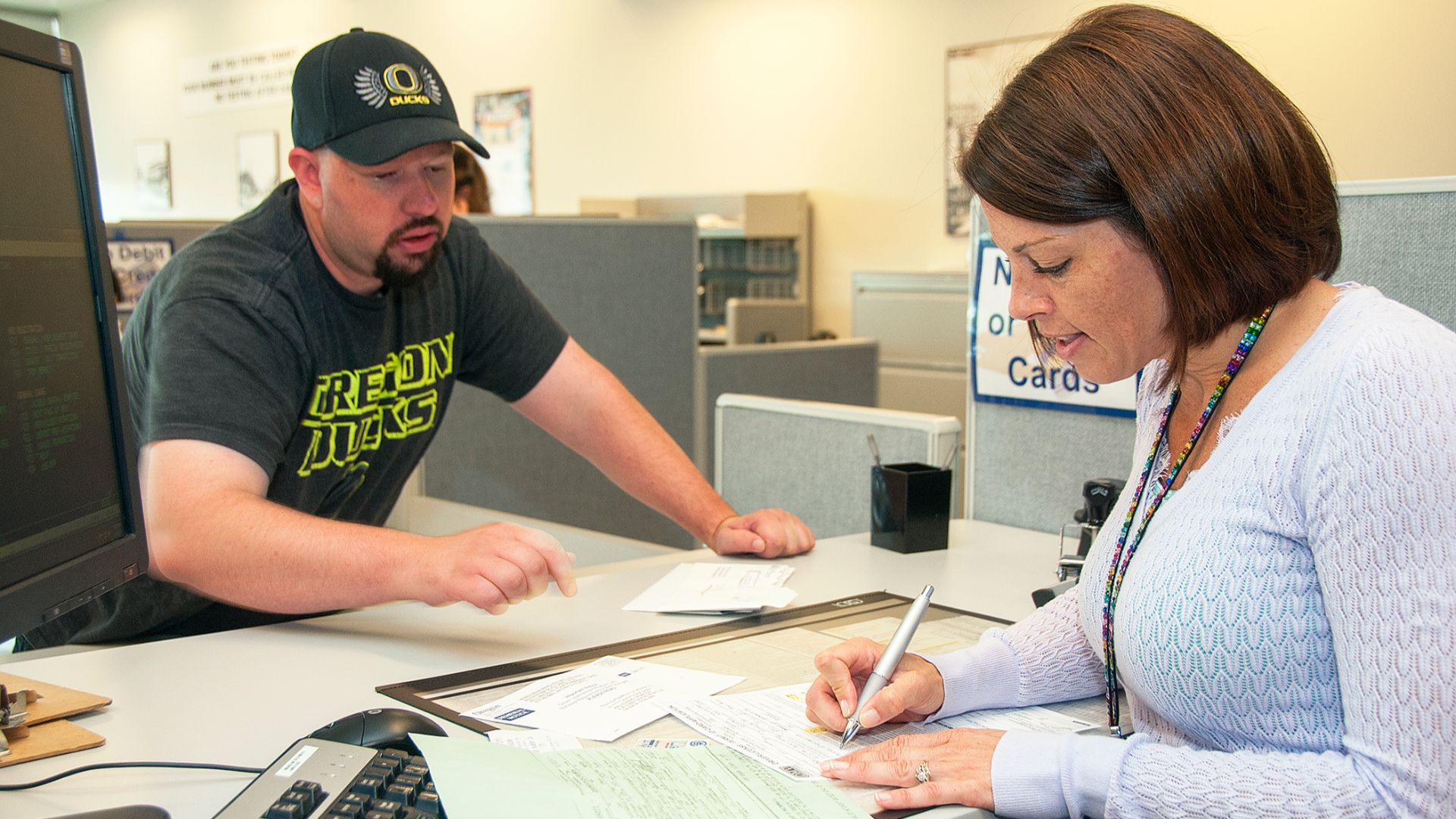 A clerk at DMV goes over a form with a customer.