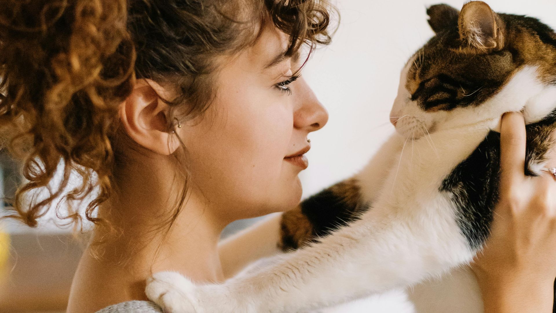 Young woman with curly hair holding a cat in a cozy indoor setting in Istanbul.