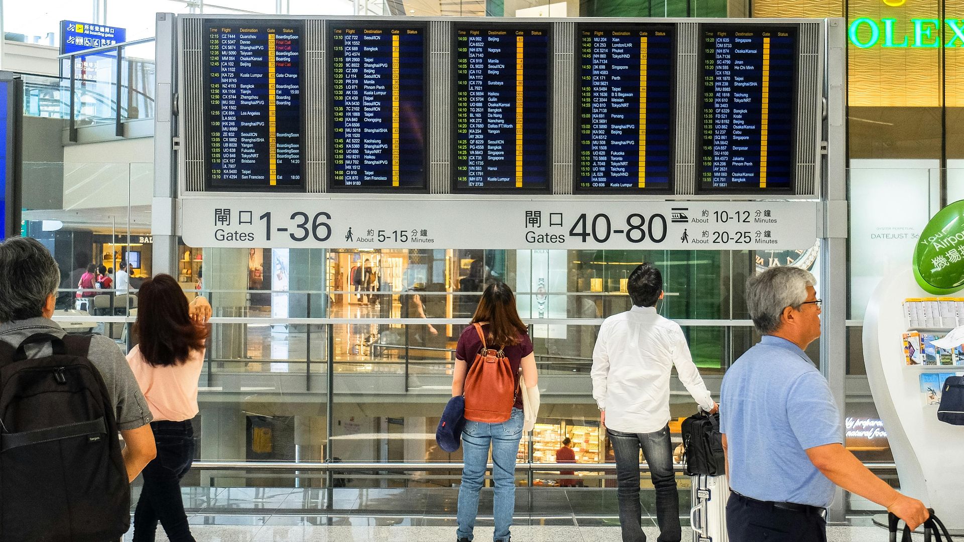 Passengers checking the departure board at Hong Kong International Airport terminal.