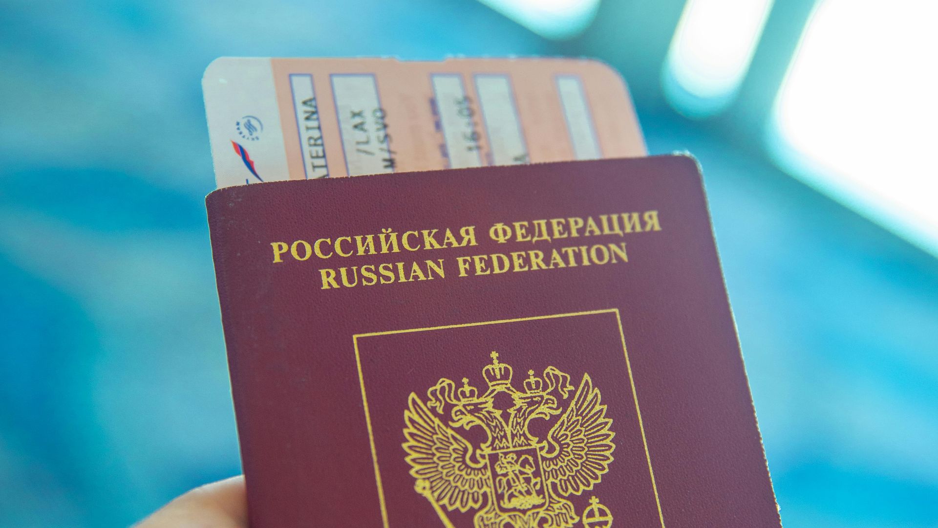 Russian passport held in hand with boarding pass peeking out, ready for travel.