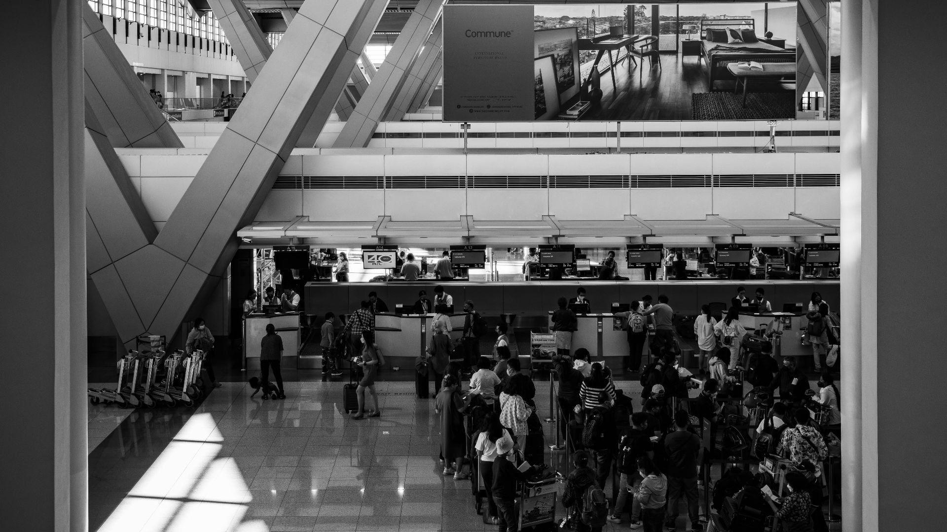 Black and white image of travelers at a bustling airport in Pasay, capturing the essence of global travel.