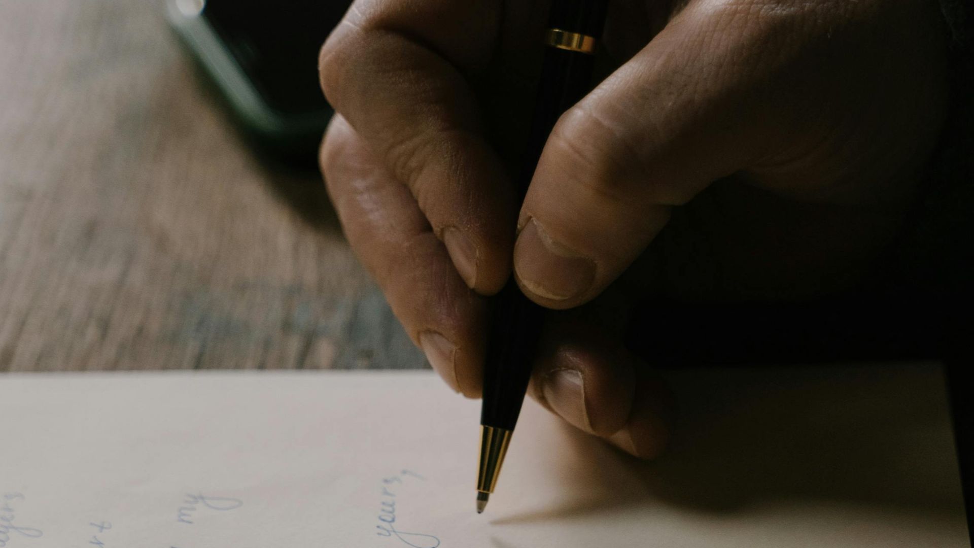 Close-up photo capturing person handwriting on paper with a pen.