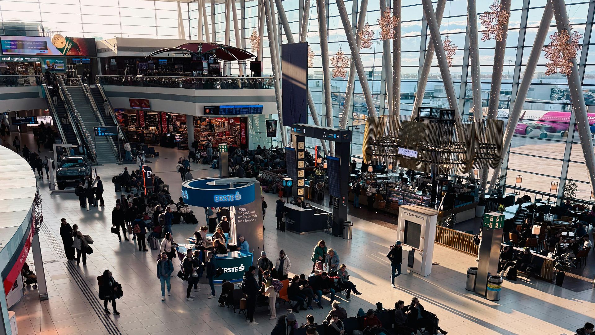 A bustling airport terminal with travelers waiting and moving through the space.