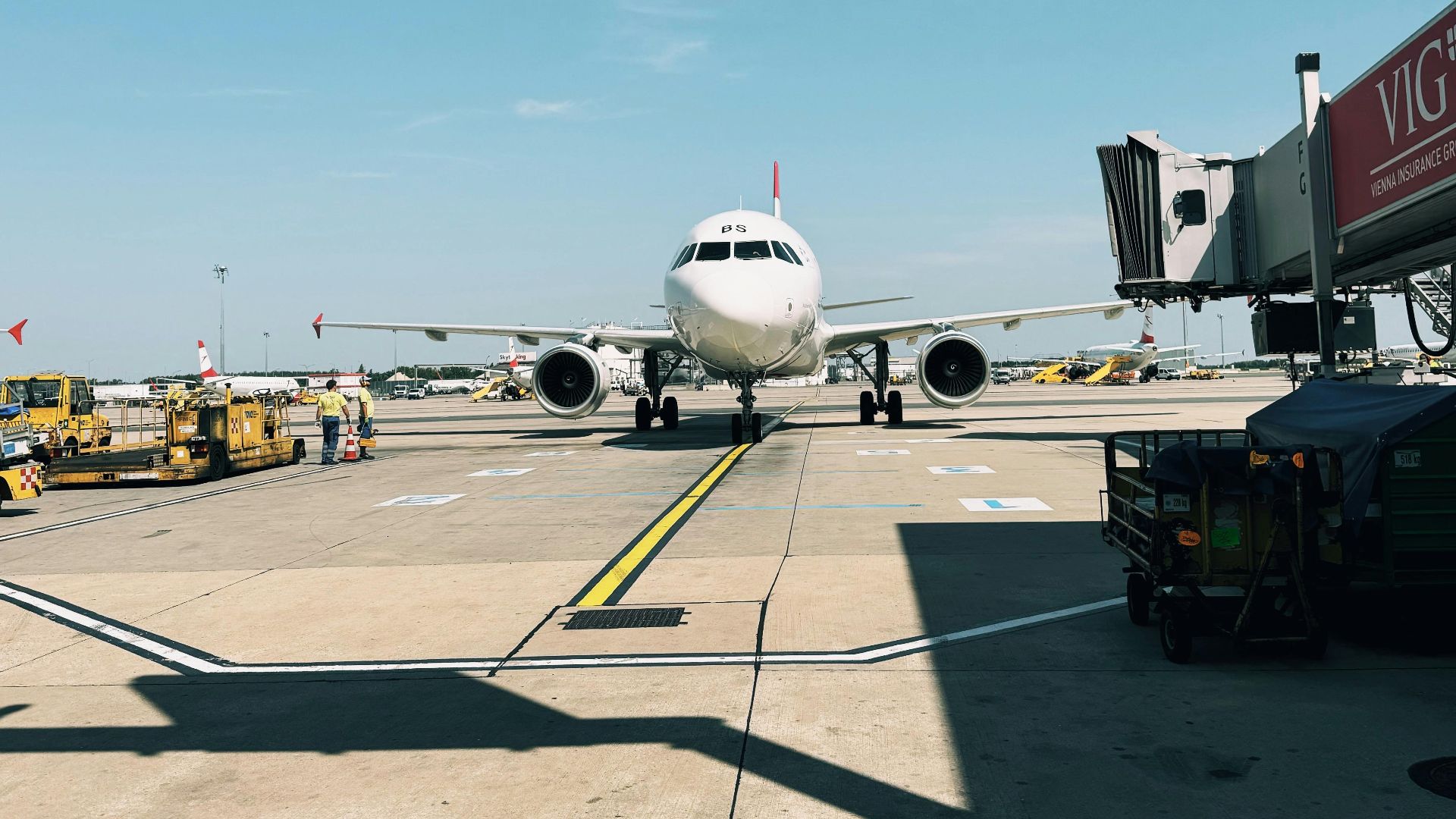 Airplane parked at terminal gate, ready for boarding under clear blue sky.