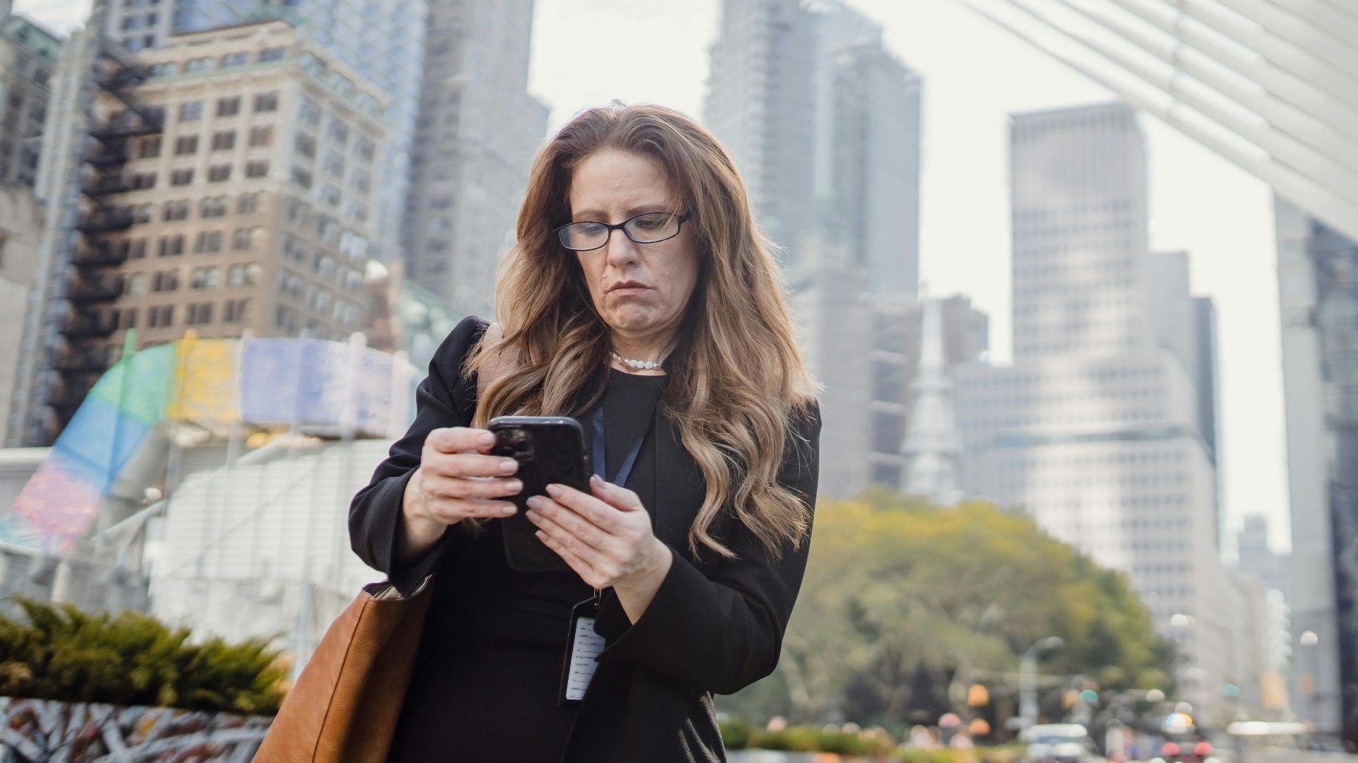 Businesswoman on phone in city street against modern skyscrapers.