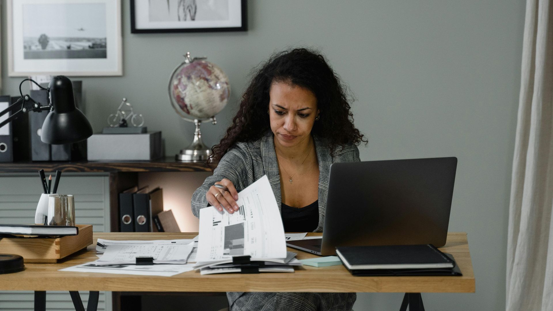 Focused professional adult reviewing documents at desk in a modern office setting.