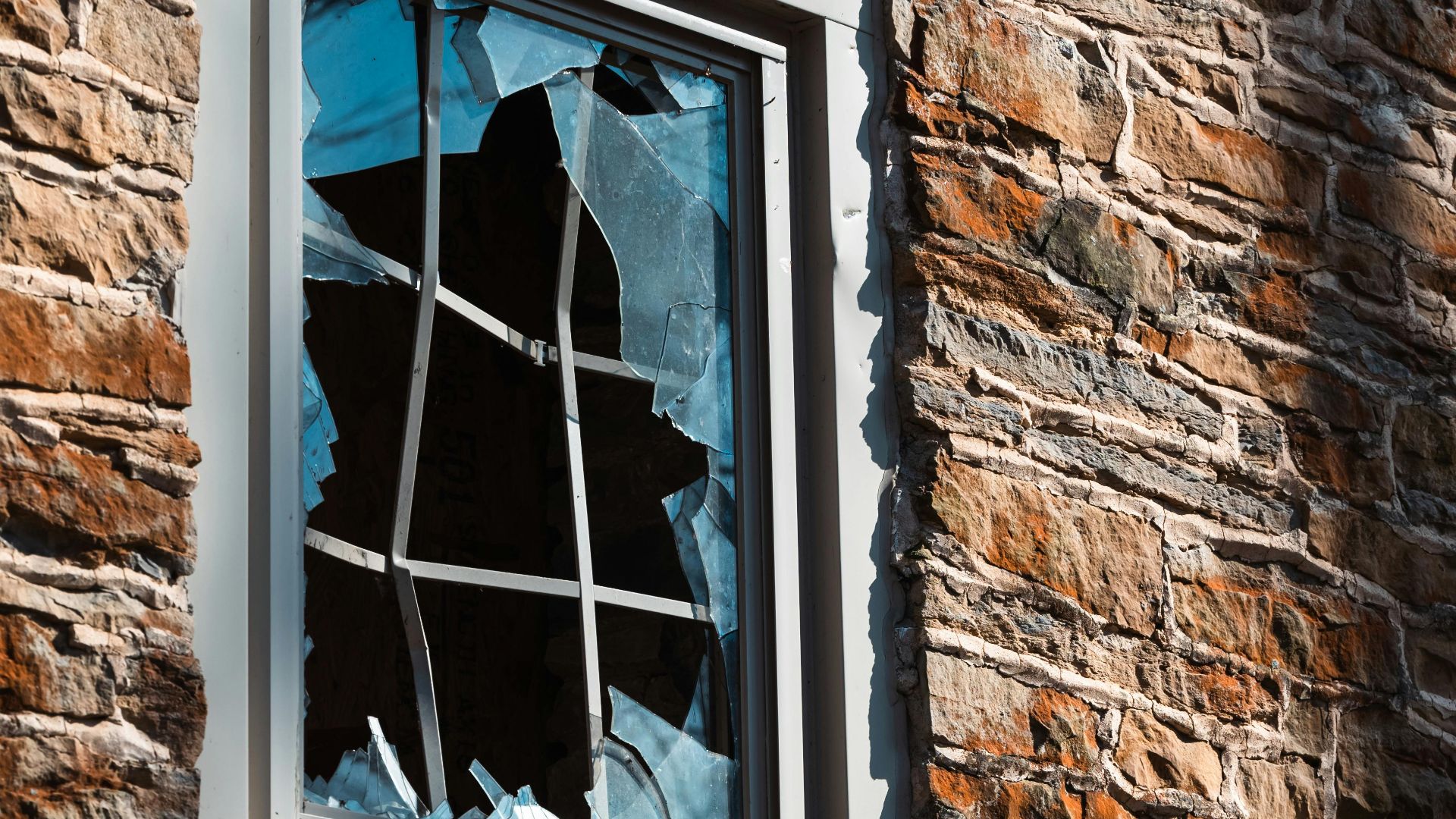 A broken window on a rustic brick wall capturing the essence of urban decay.