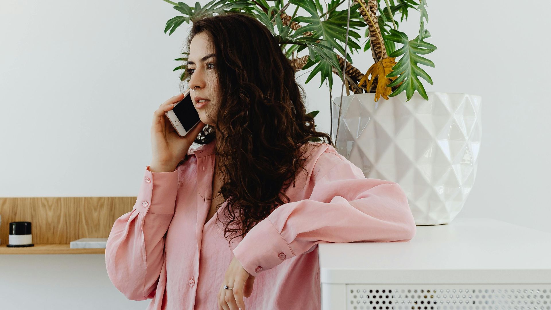 Businesswoman in office environment talking on phone, casual and relaxed setting.