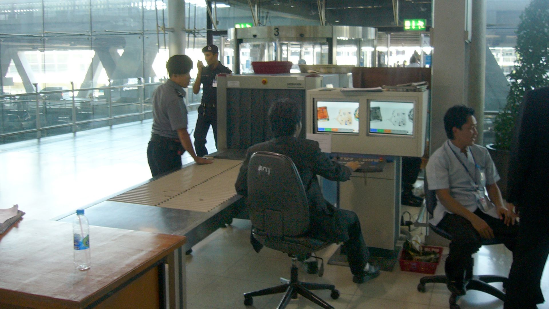 Luggage screening device at Suvarnabhumi International Airport, Bangkok, Thailand. This security post is located for entering the airport which means all people (visitors and passengers) have to pass such a control. Another control will be for boarding luggage before entering the secured area (passengers only). View towards the street.