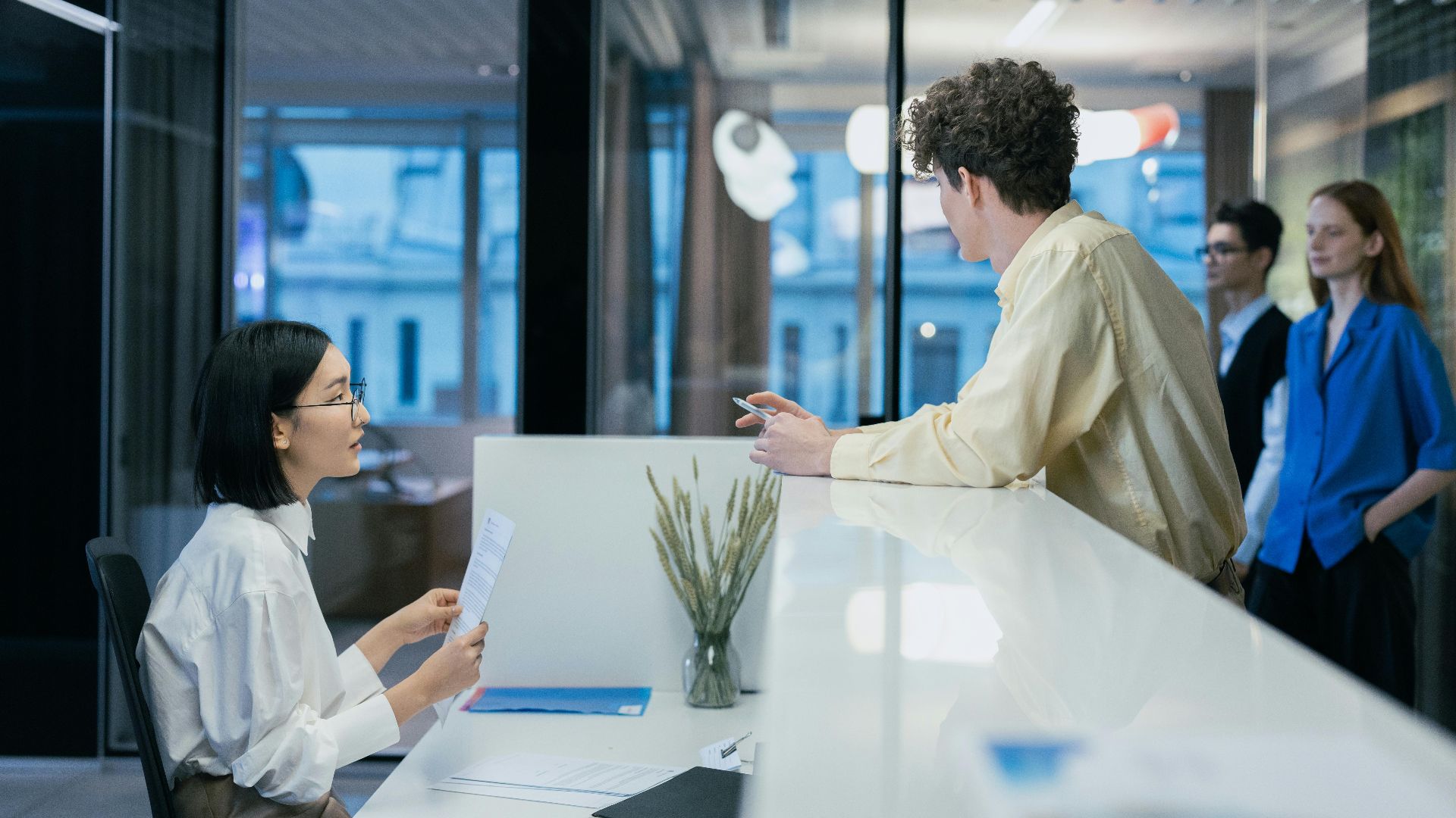 Employees interacting at a sleek office reception desk, fostering professional collaboration.