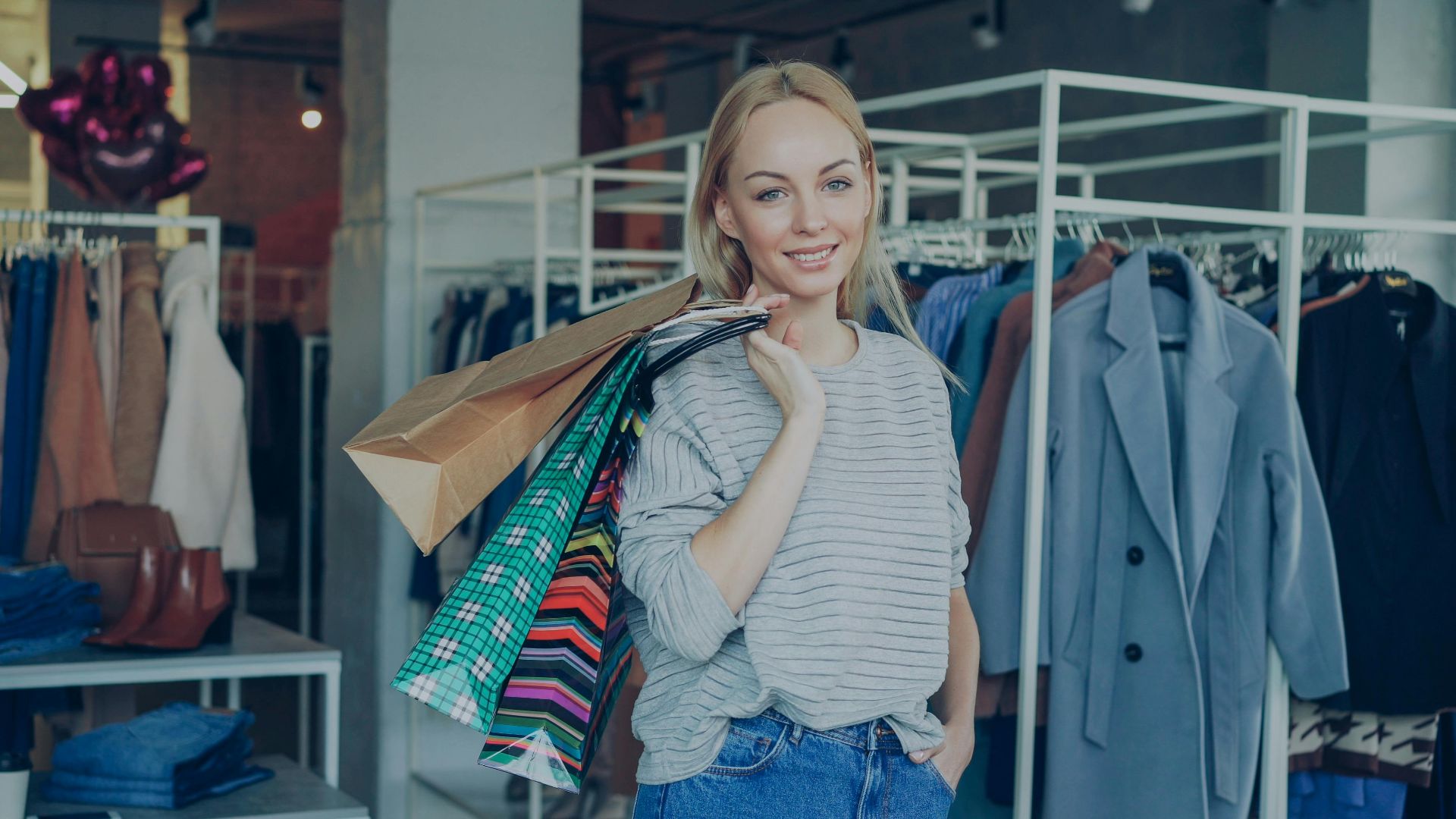 Smiling woman holding shopping bags in a trendy fashion boutique.