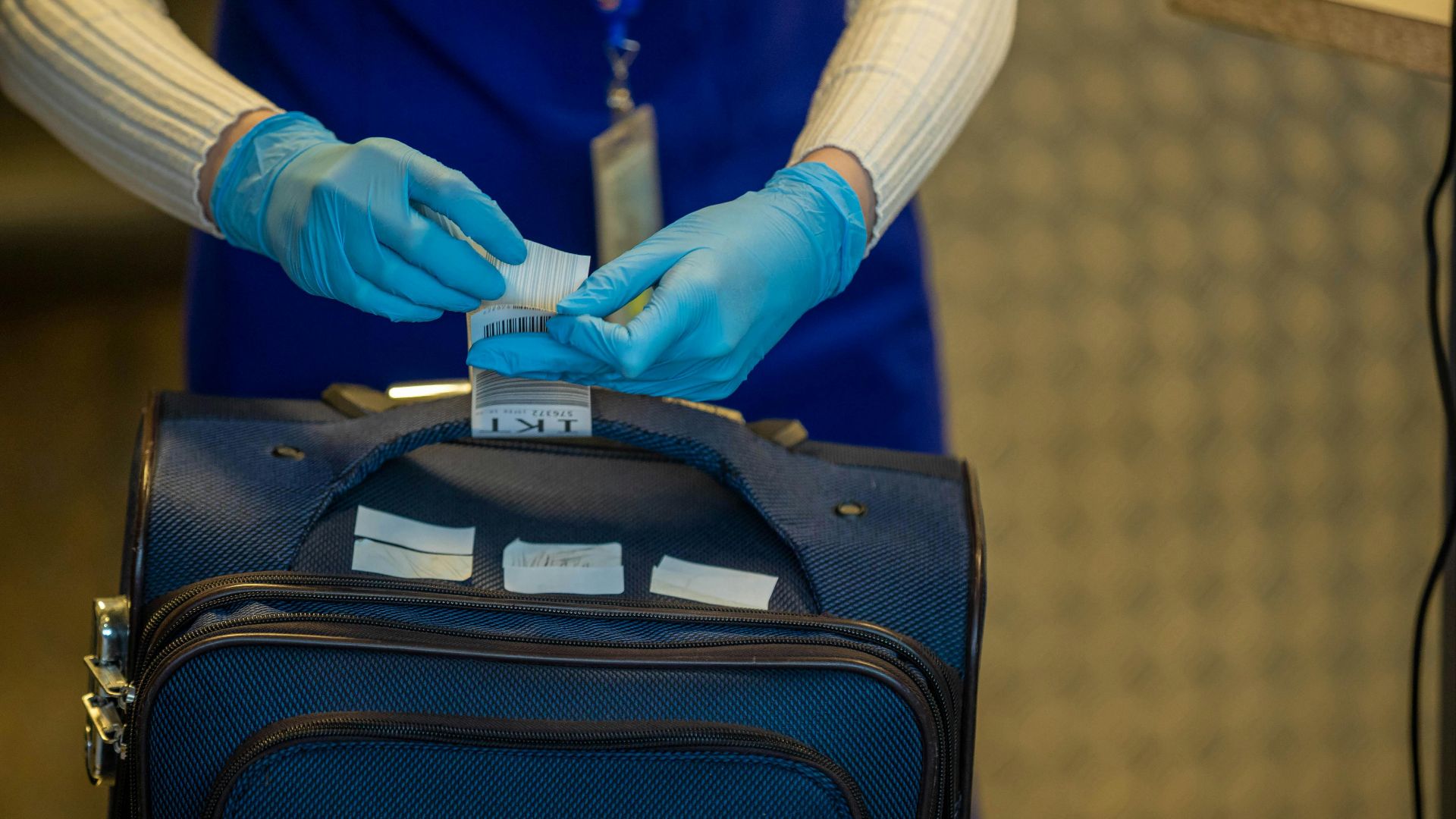Close-up of airport security process with gloved hands inspecting luggage tags.