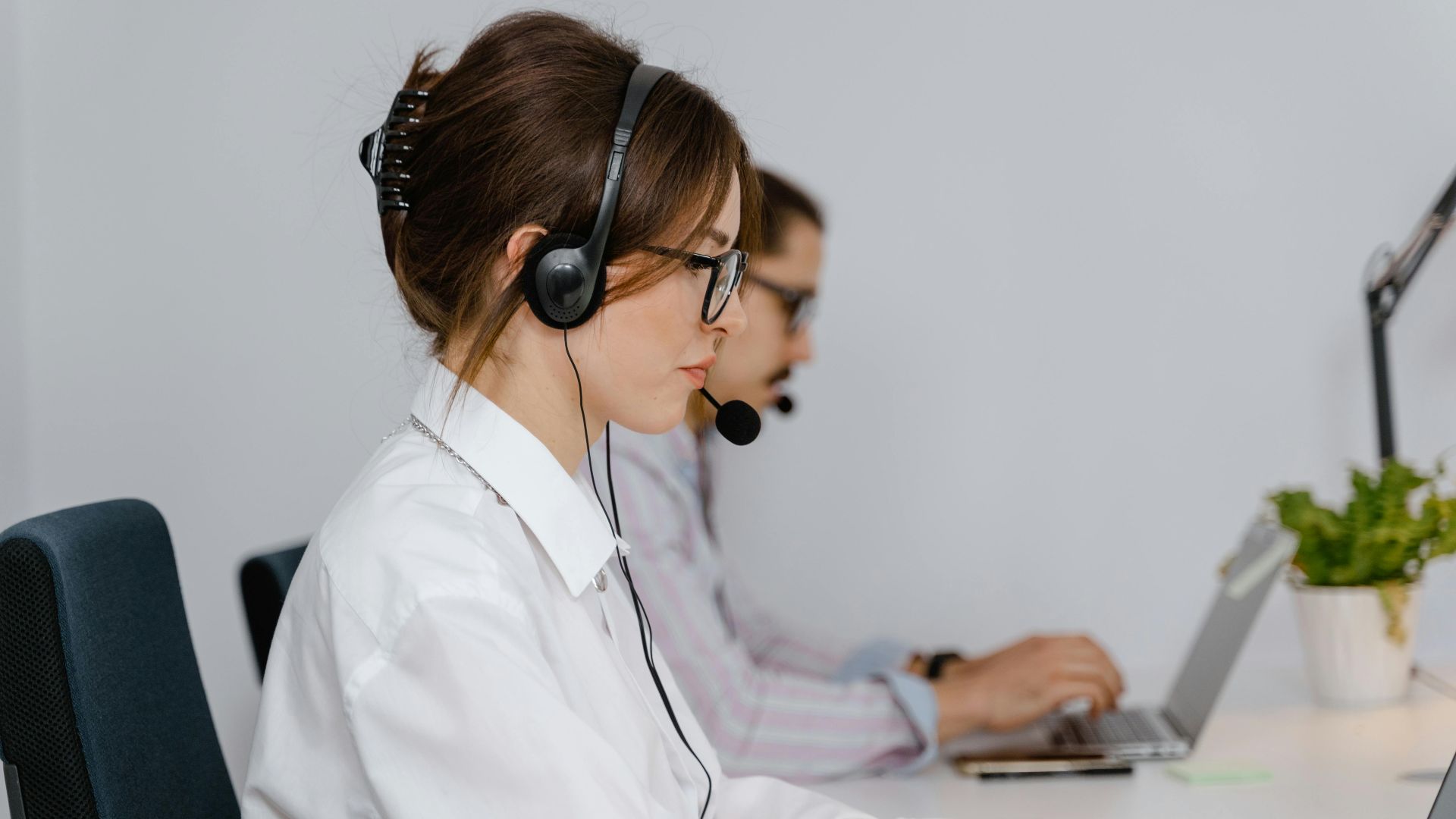 Customer service agents working at call center with headsets, focused on providing support.