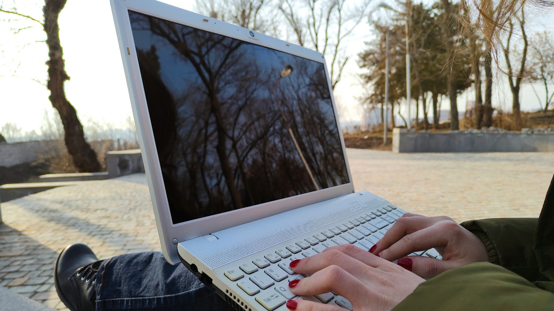a person typing on a laptop on a bench