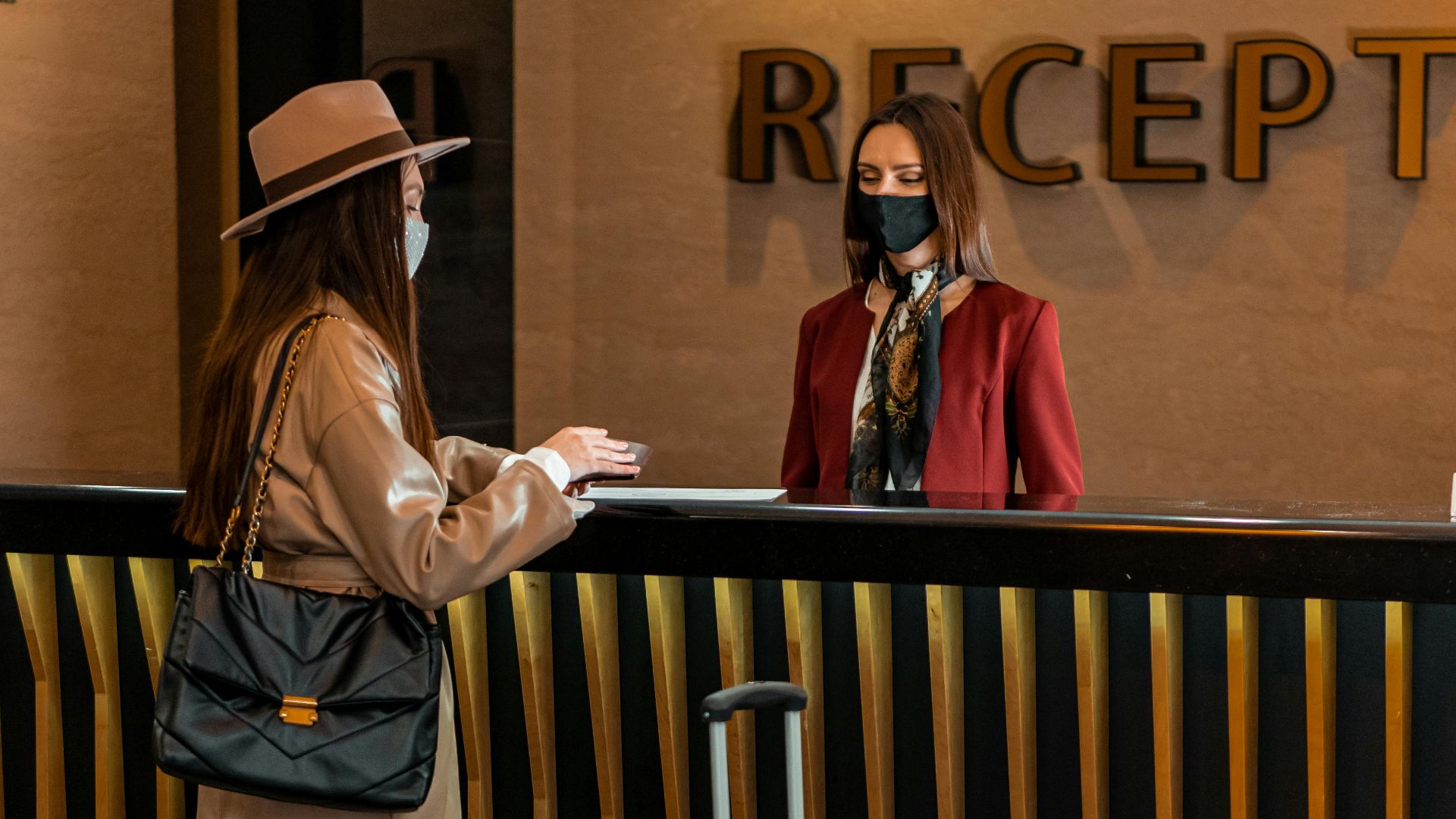 Businesswoman checking into a hotel at a stylish reception desk, engaging with staff.