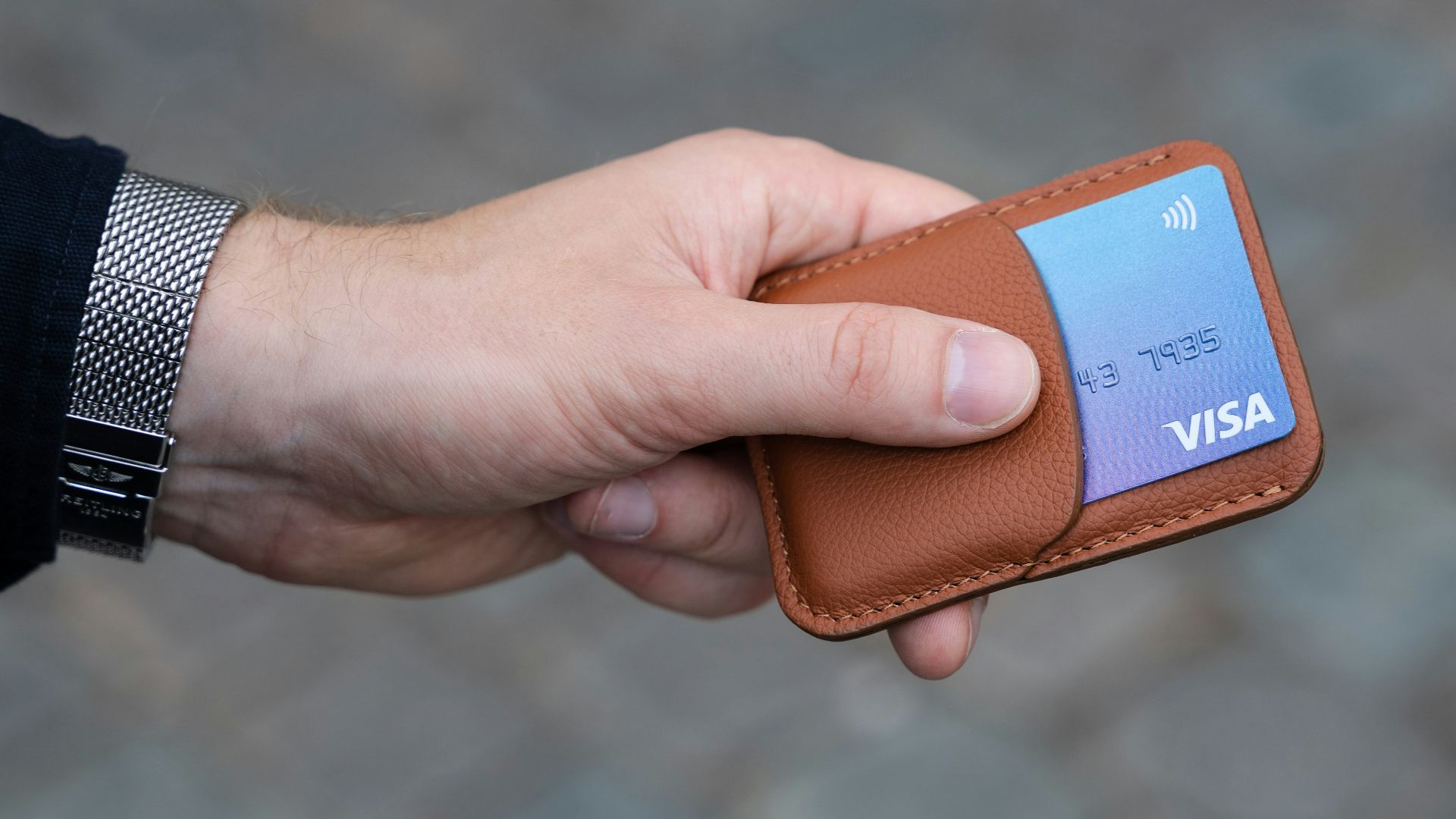 a hand holding a wallet with a credit card in it
