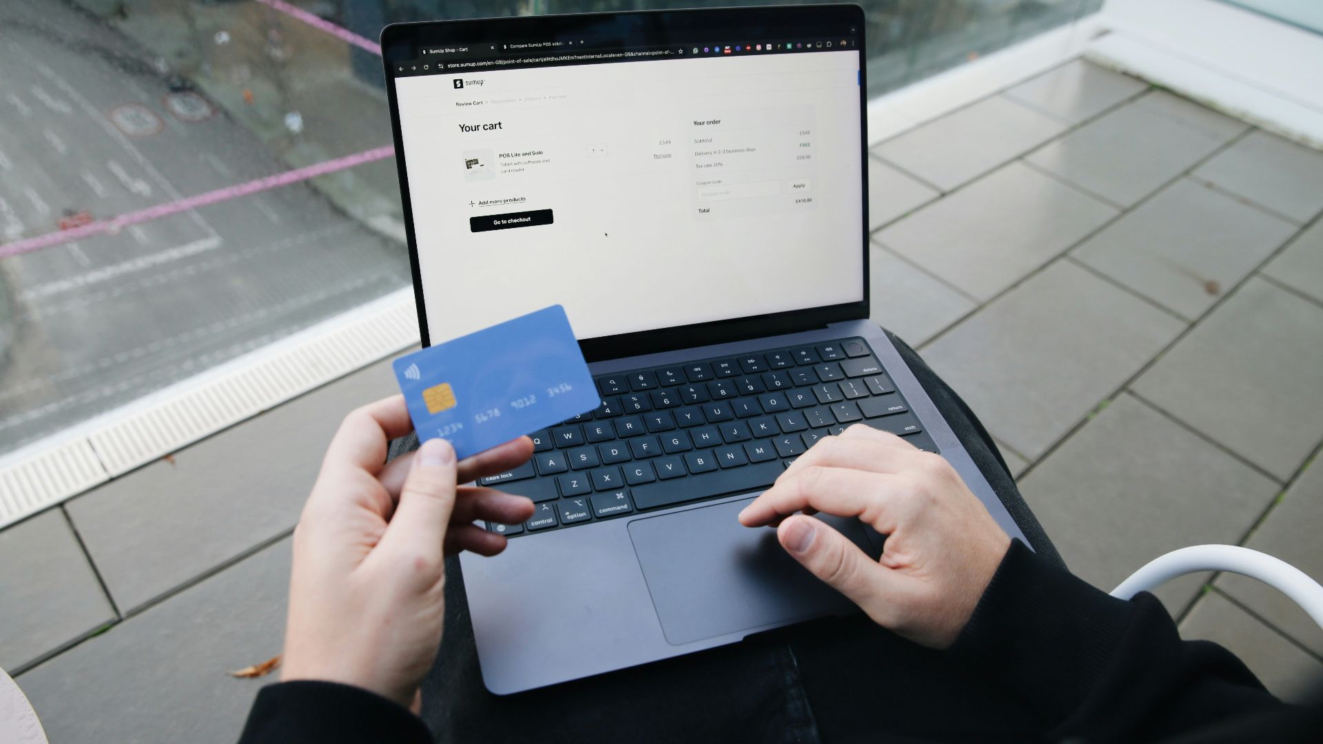 A person sitting in a chair with a laptop and a credit card