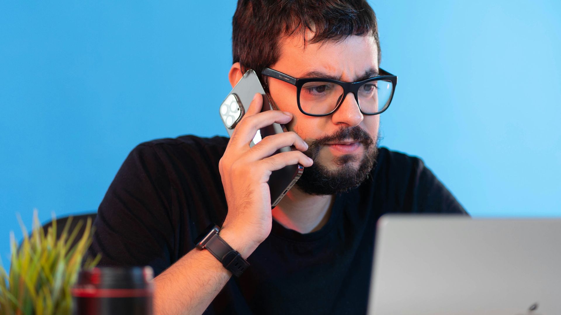 a man sitting at a desk talking on a cell phone
