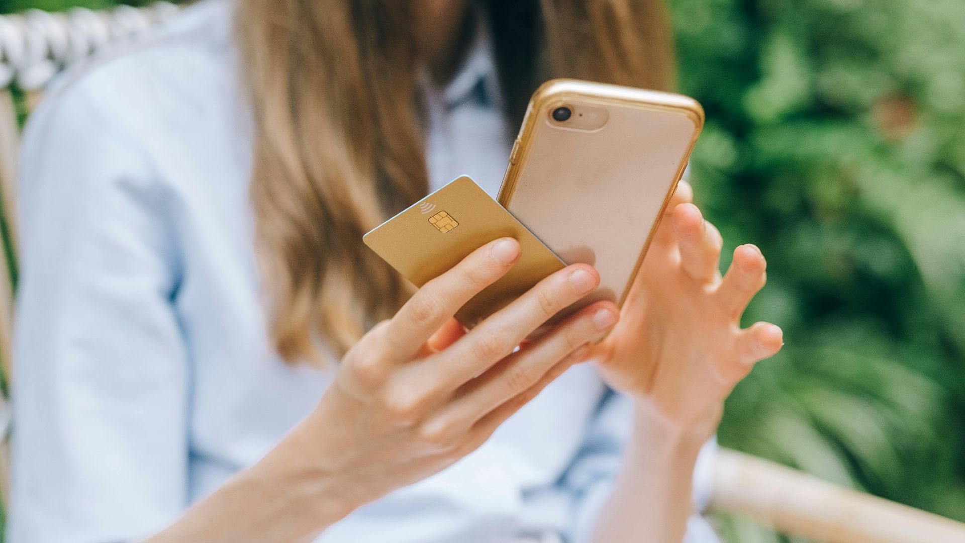 A woman making an online purchase using a smartphone and credit card outdoors.