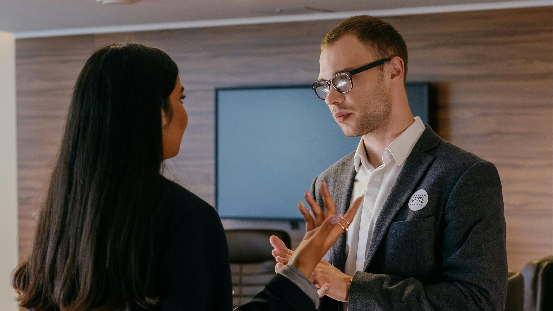 Two professionals engaged in conversation in a modern conference room setting.