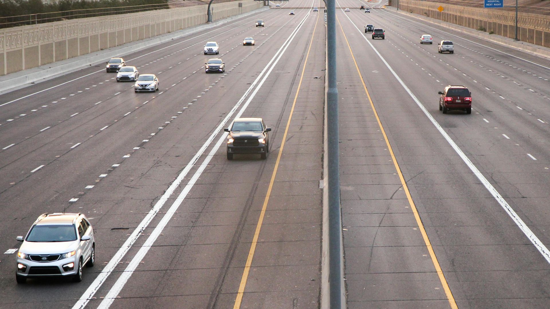 Aerial view of a deserted highway with few cars during dusk, depicting calm traffic conditions.