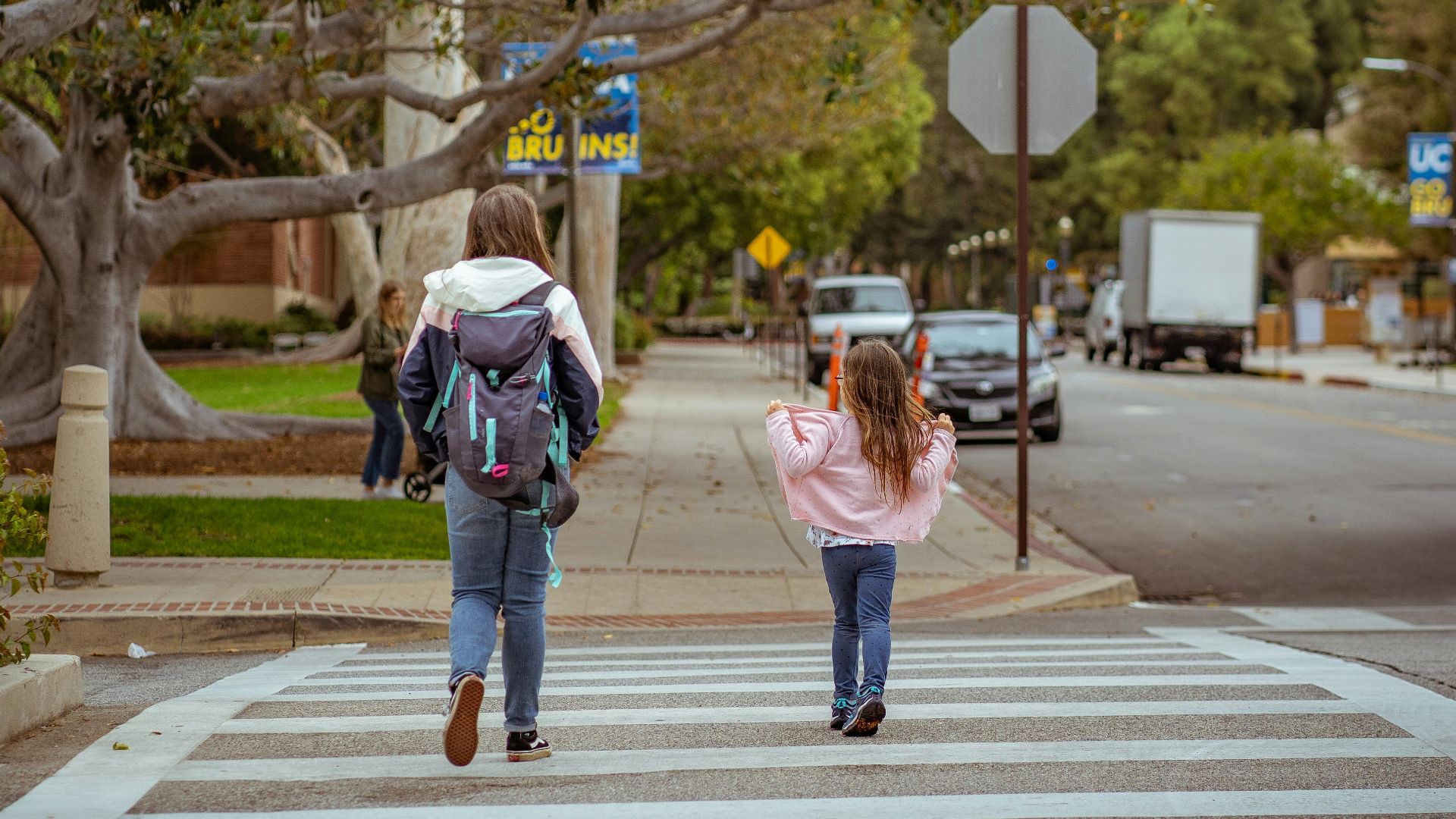 Two children crossing an urban street in Los Angeles on a cloudy day.