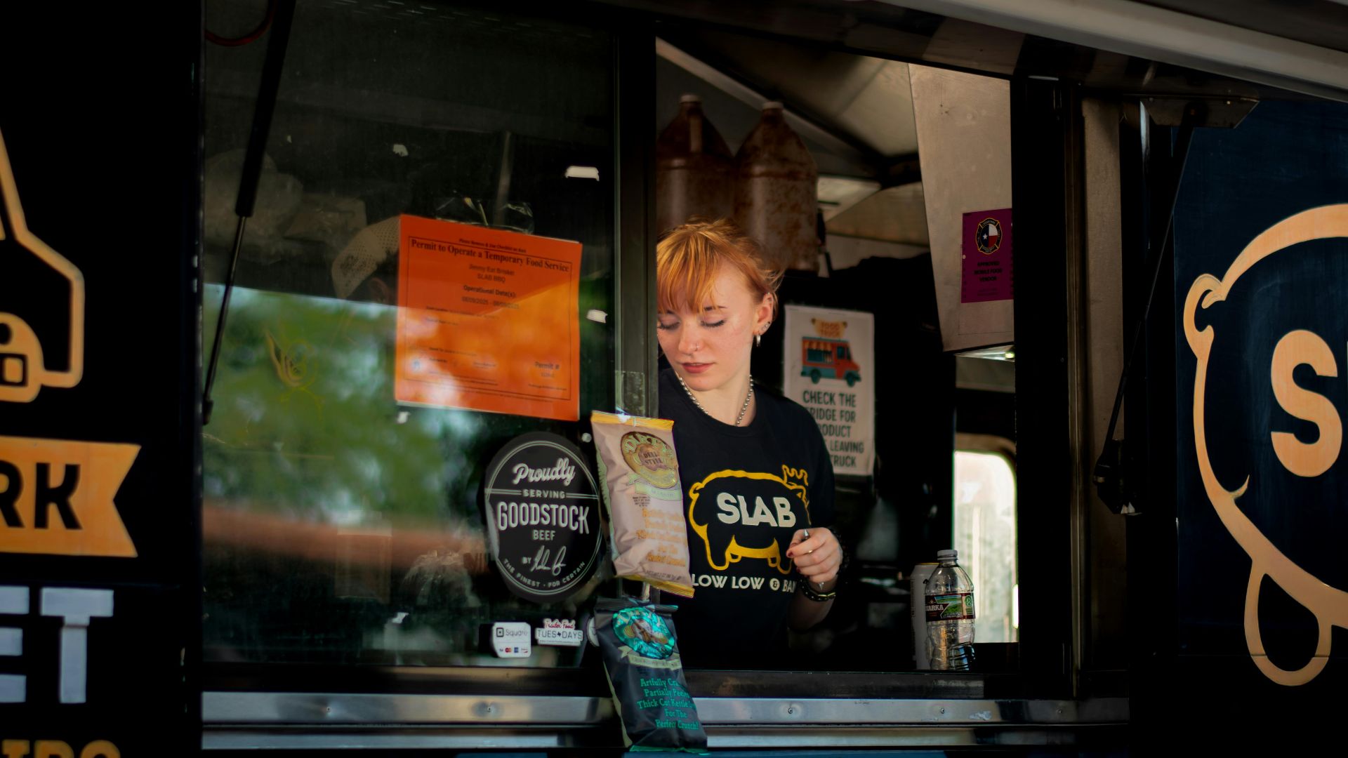 A female vendor serves from a food truck in Austin, TX.