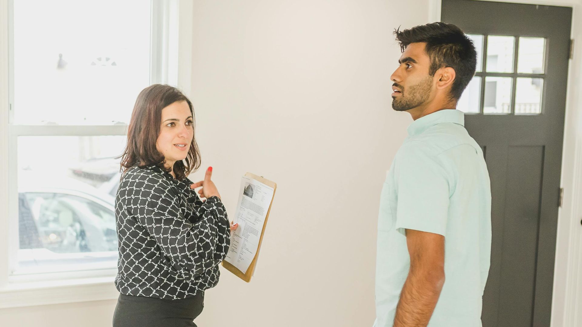 Real estate agent showing a modern home interior to a potential buyer.