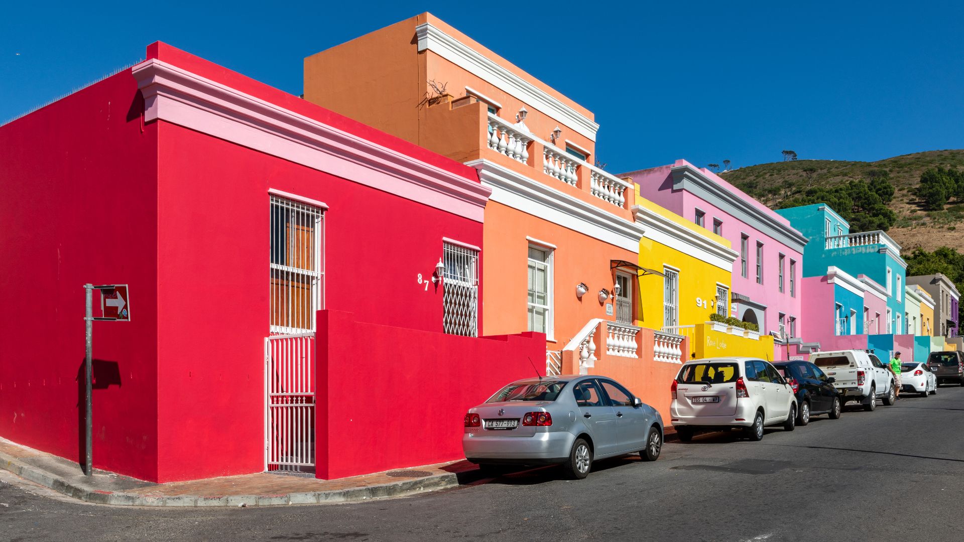 Colorful houses in Wale Street, Cape Town, Western Cape, South AfricaBo-Kaap is a historic neighborhood above the center of Cape Town. It was established in the 18th century when the Dutch colonial administration built houses for enslaved people from Southeast Asia, India, and East Africa. Many of them were Muslims and later became known as “Cape Malays”.After their liberation in the 19th century, Bo-Kaap developed into a center of Islamic culture in the Cape. Mosques such as the Auwal Mosque from 1794 bear witness to this tradition.The colourfully painted houses, originally an expression of newly won freedom, now characterise the image of the neighbourhood. Despite gentrification, Bo-Kaap remains an important symbol of cultural heritage and resilience in South Africa.