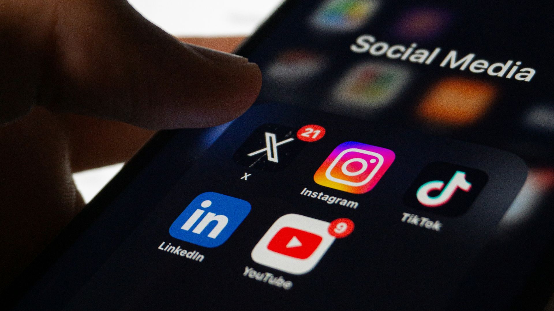 A person holding a smart phone with social media on the screen