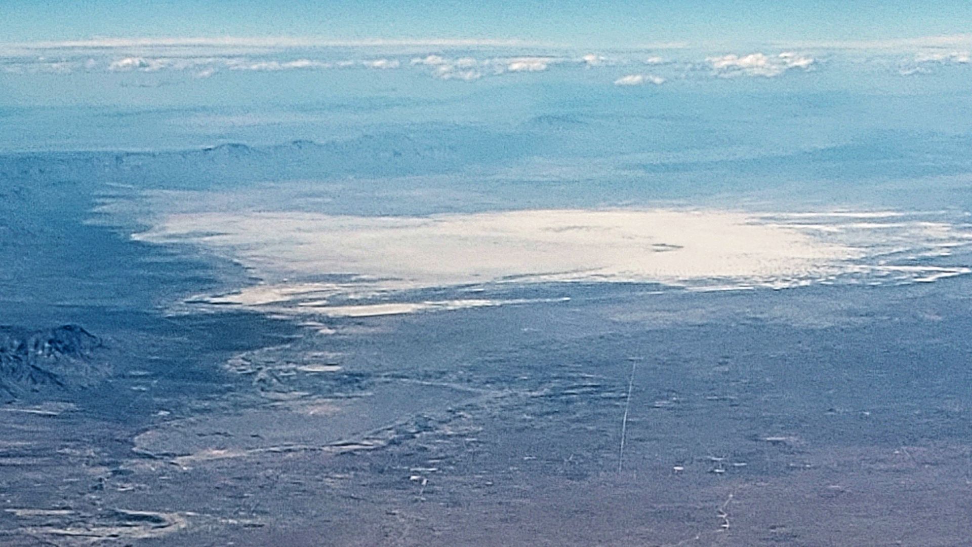 Aerial photo of White Sands National Park looking north.  The gypsum crystals that form the sand blow in from the dry lake bed below the mountains on left side of the image.