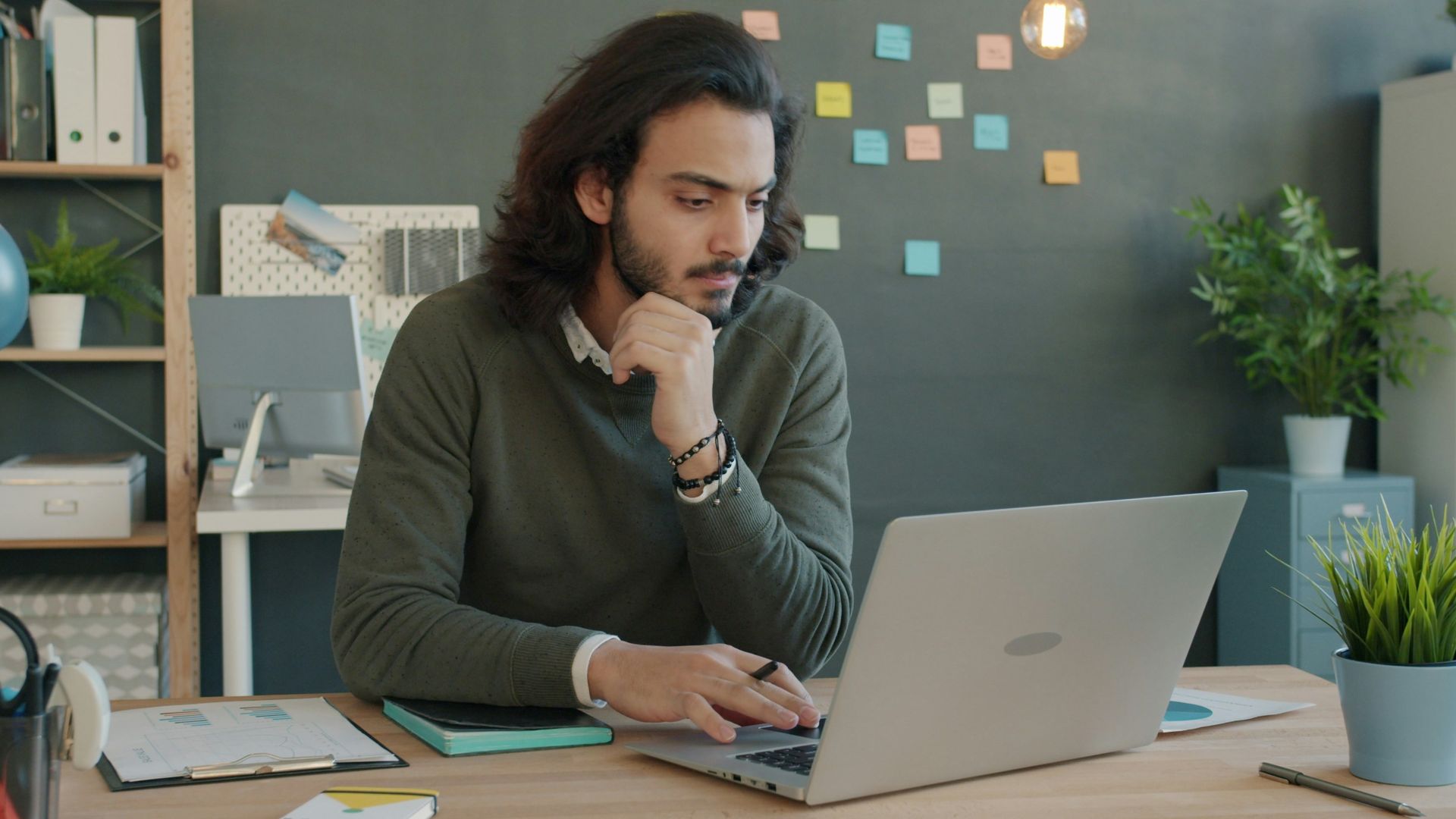 Man working on laptop in modern office space.