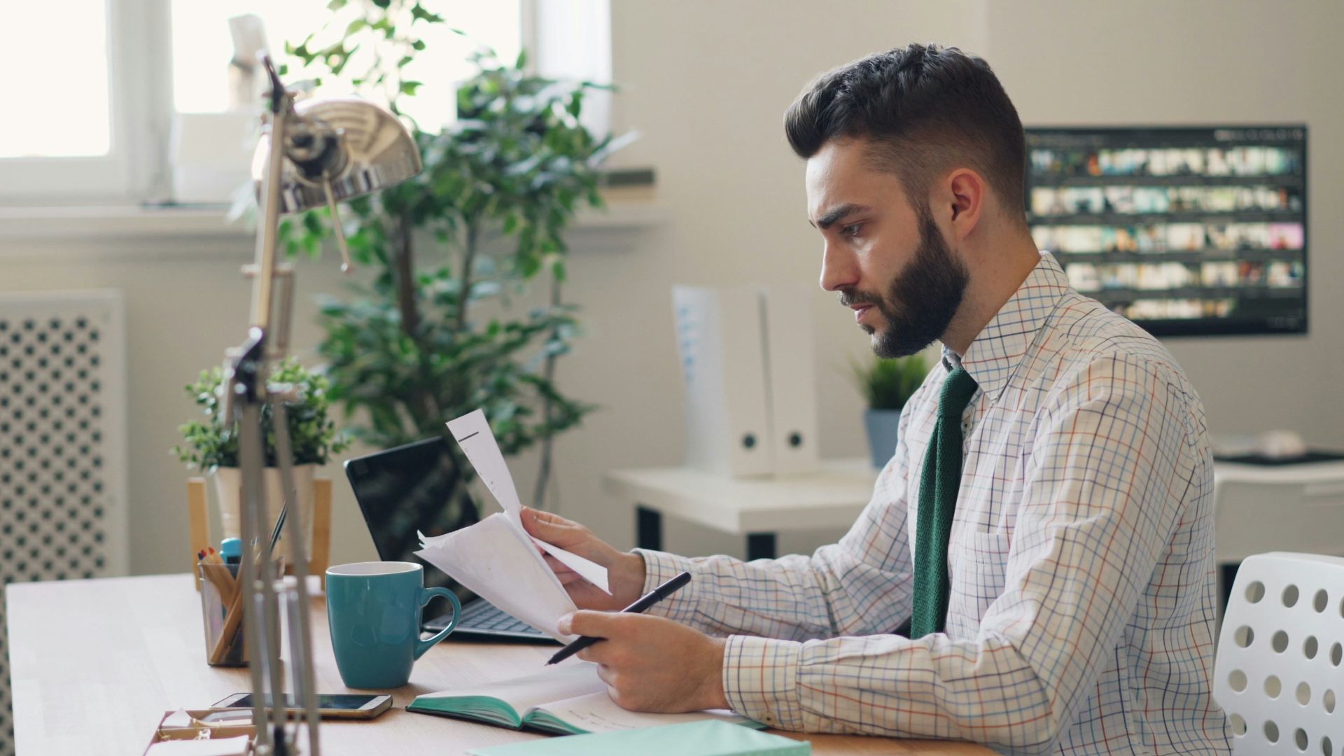 a man sitting at a desk with a laptop and papers
