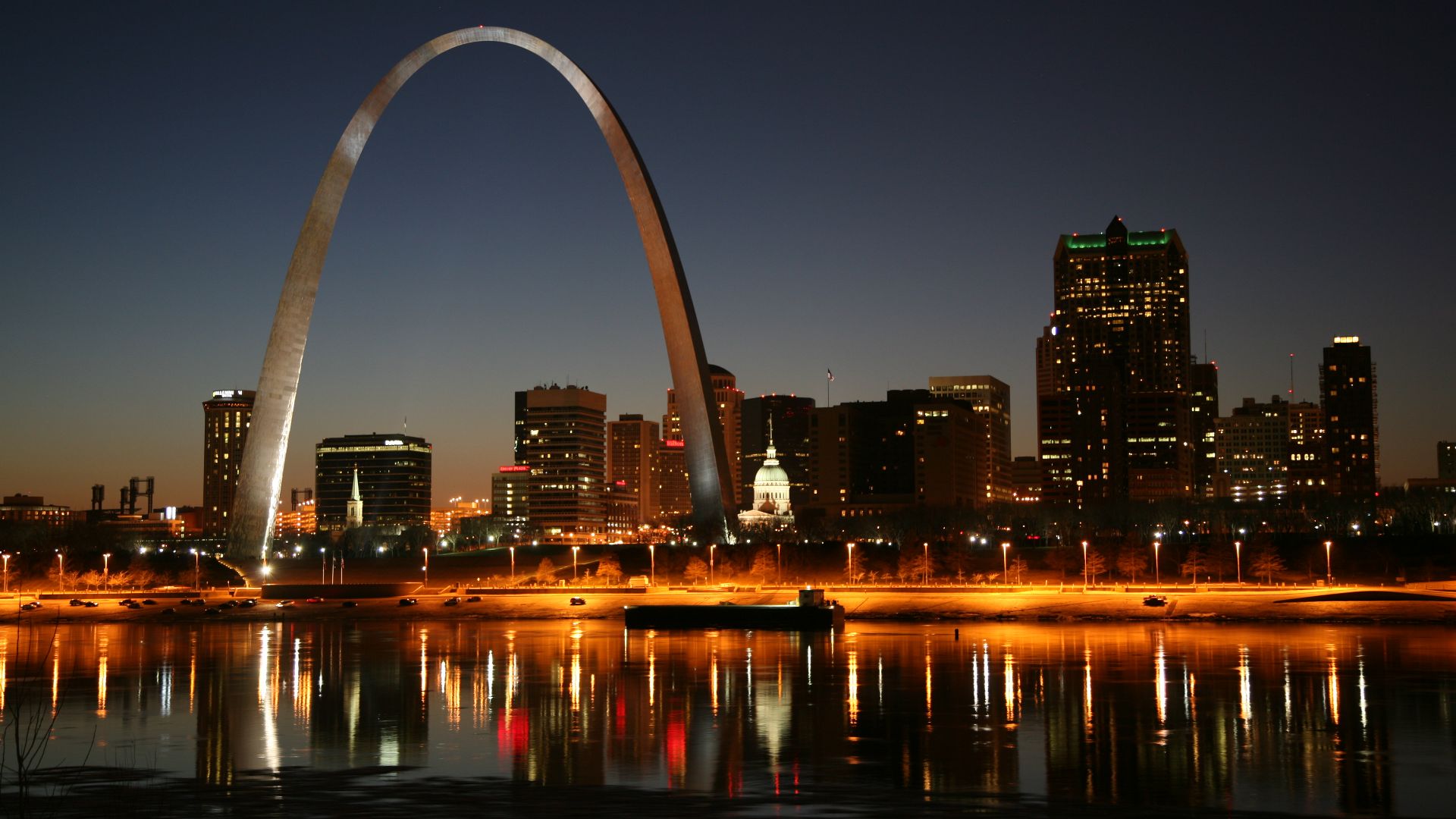 St. Louis on the Mississippi river by night/ Jefferson National Expansion Memorial aka. Gateway Arch and Old Courthouse are visible.