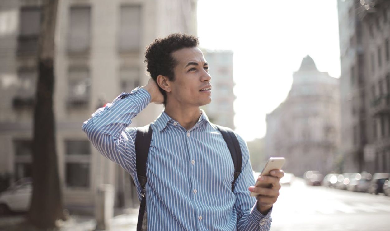 Thoughtful man using smartphone on street