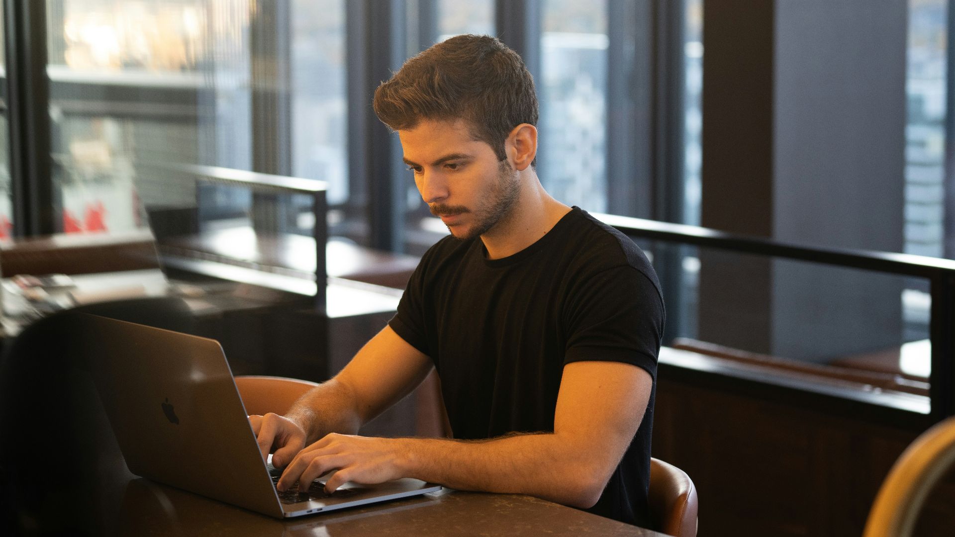 man in black crew neck t-shirt using macbook
