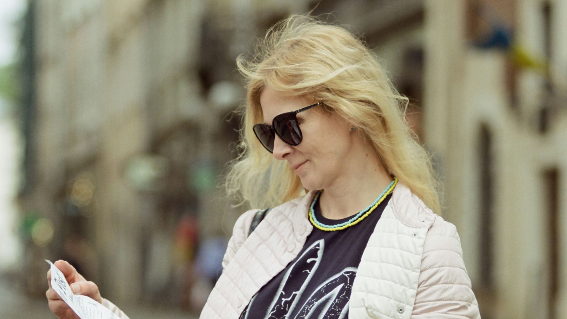 a woman standing on a street reading a paper