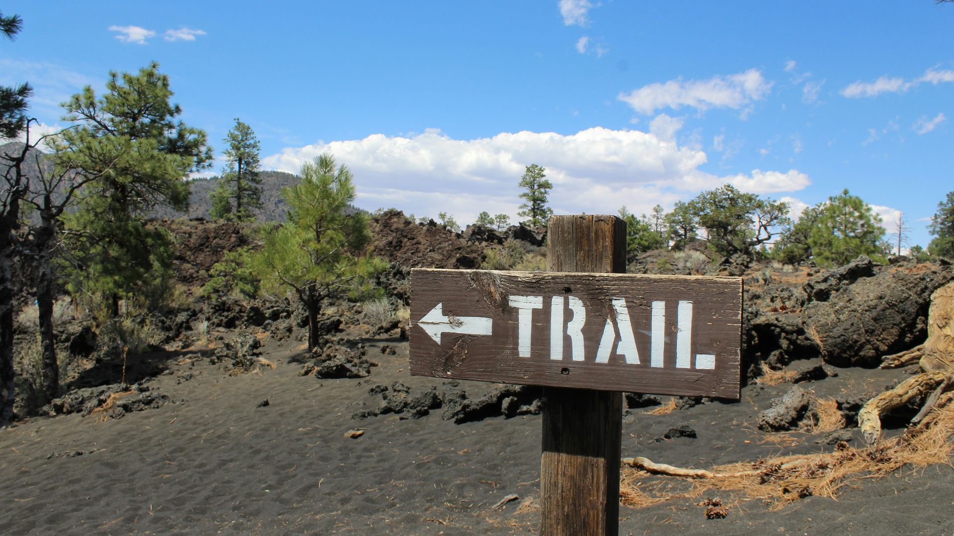 a wooden sign pointing to a trail in the mountains