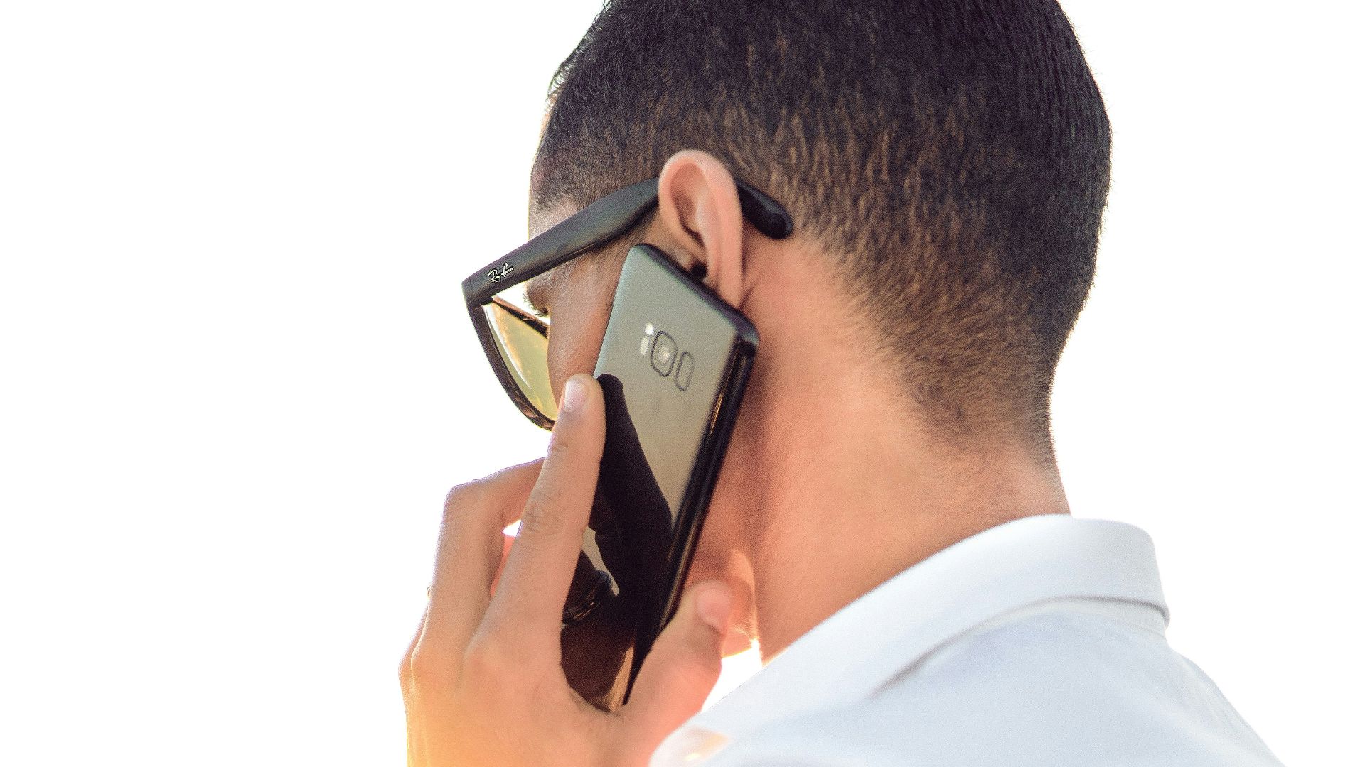 man holding smartphone standing in front of calm body of water