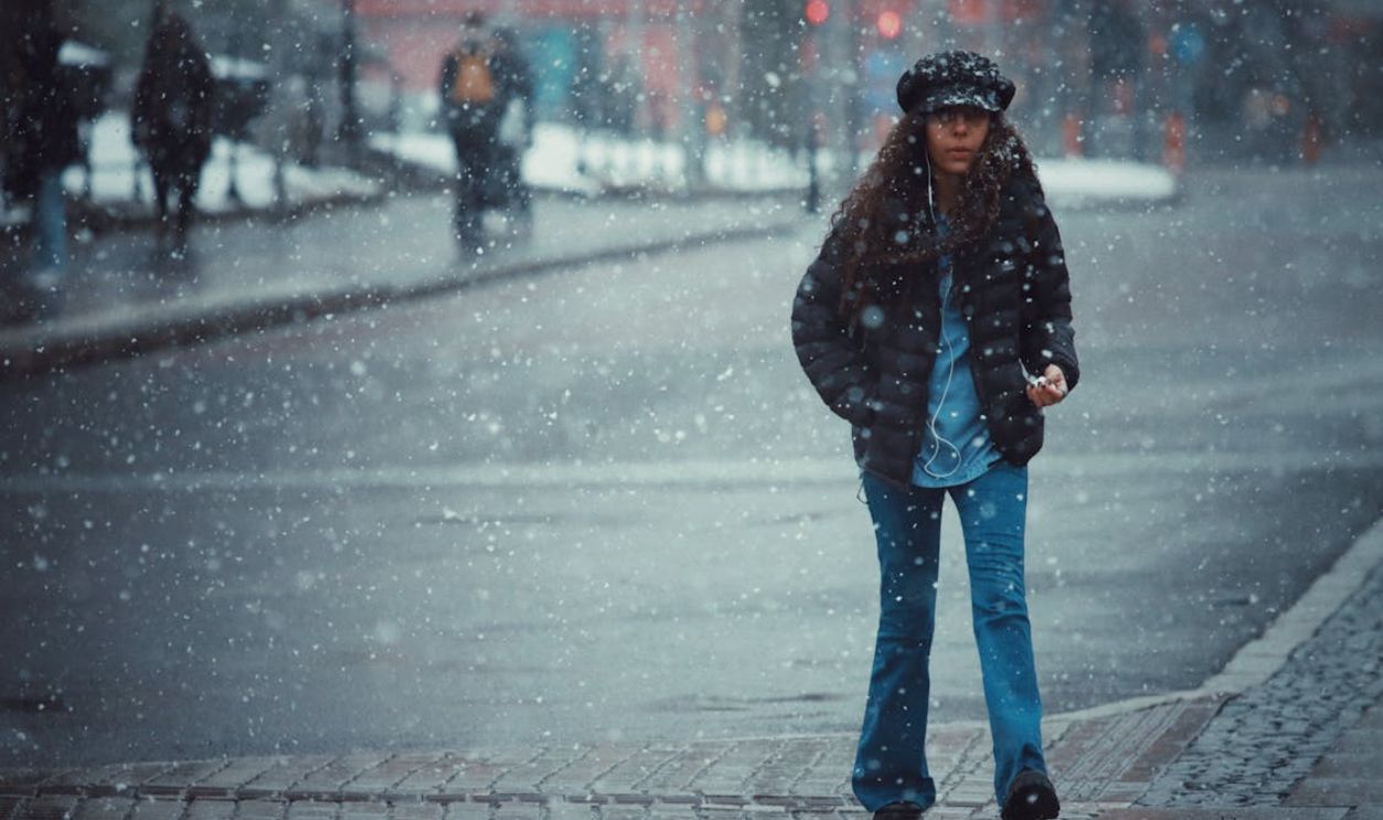 A Woman Walking While Snowing