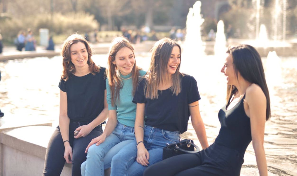 Photo of Women Laughing While Sitting Near Water Fountain