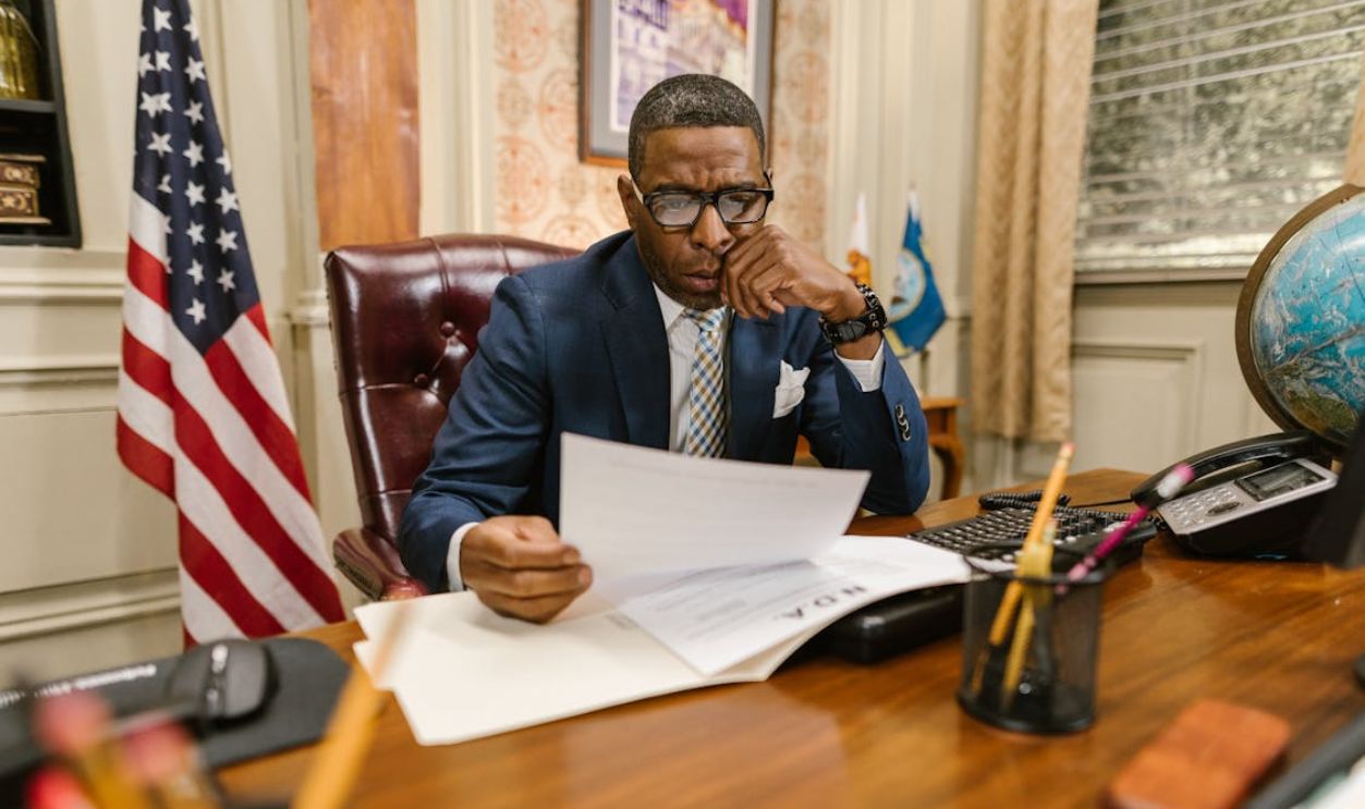 A Man in Blue Suit Jacket Holding White Printer Paper