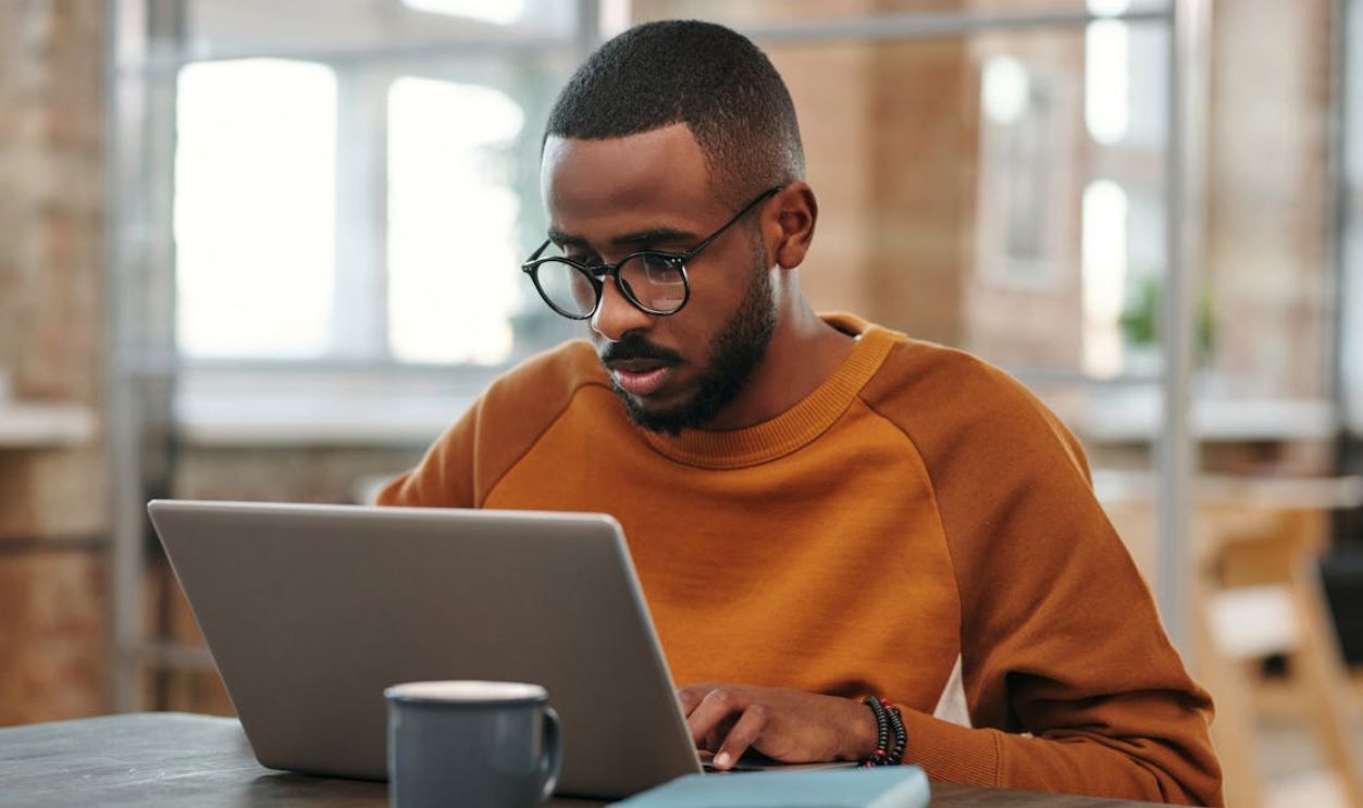 A Man in Sweater Using Laptop