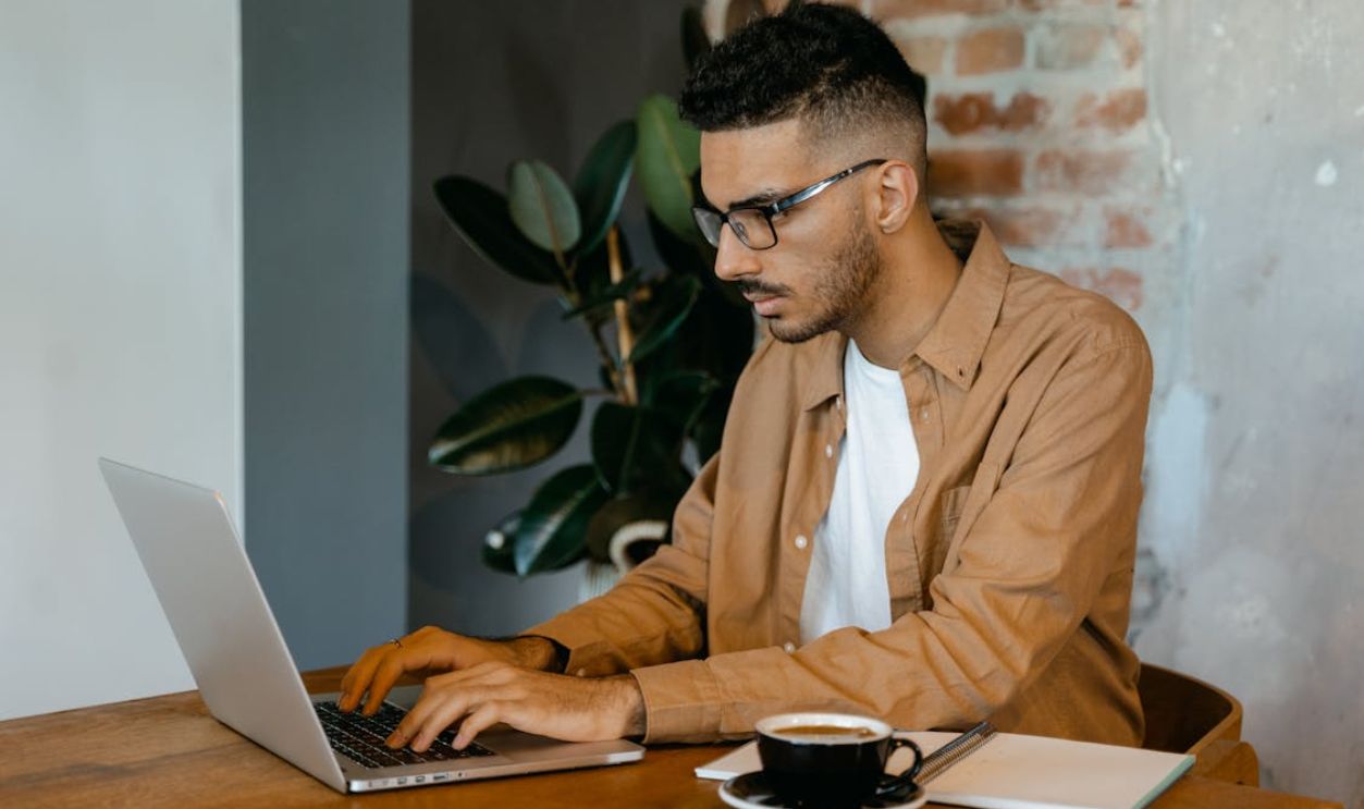 Man in Brown Dress Shirt Typing on a MacBook Pro